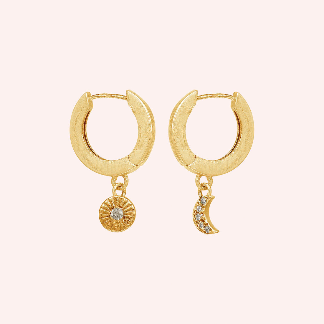 Silver_hoop_earrings_in_gold_plated_silver_with_sun_and_moon_charms_at_front_angle_view_on_solid_pink_background