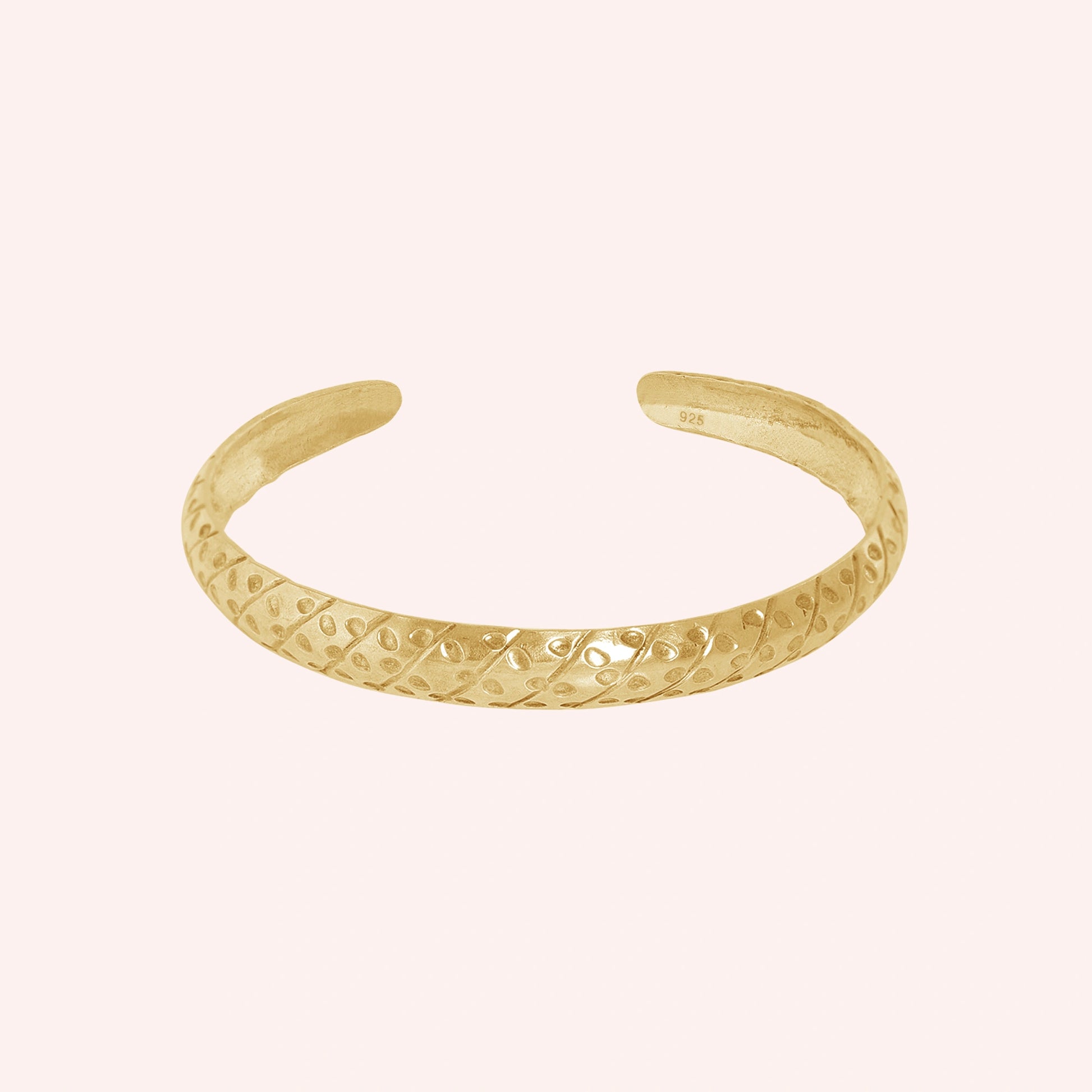 Adjustable_bangle_in_gold_plated_silver_with_a_textured_design_band_at_front_angle_view_on_solid_pink_background