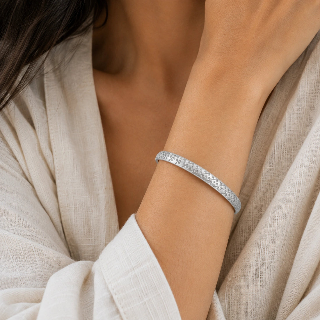 Adjustable_bangle_in_gold_plated_silver_with_a_textured_design_band_at_slight_angle_view_on_soft_fabric_background