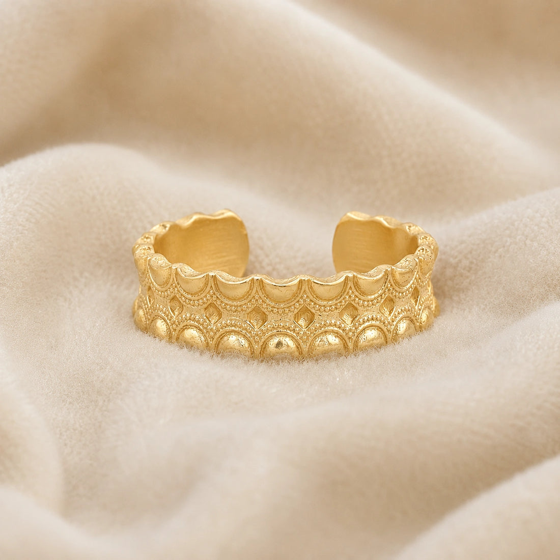 Adjustable_ring_in_gold_plated_silver_with_handcrafted_deisgn_at_front_angle_on_soft_fabric_background