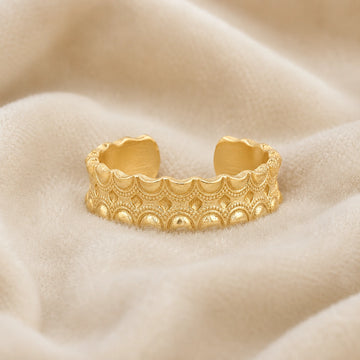 Adjustable_ring_in_gold_plated_silver_with_handcrafted_deisgn_at_front_angle_on_soft_fabric_background