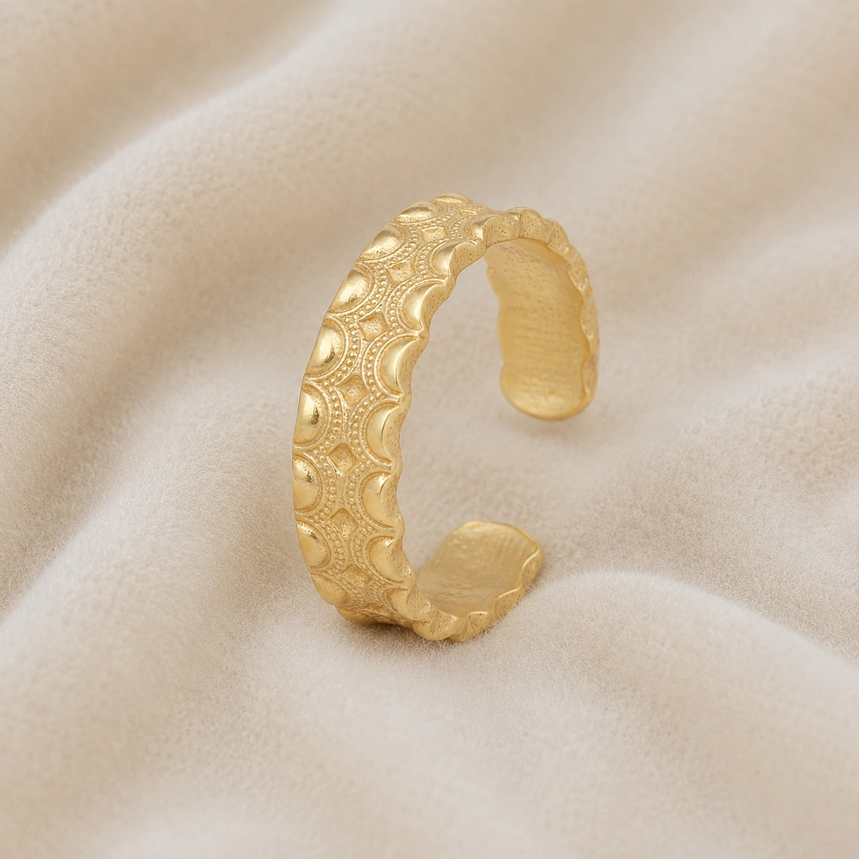 Adjustable_ring_in_gold_plated_silver_with_handcrafted_deisgn_at_slight_angle_on_soft_fabric_background