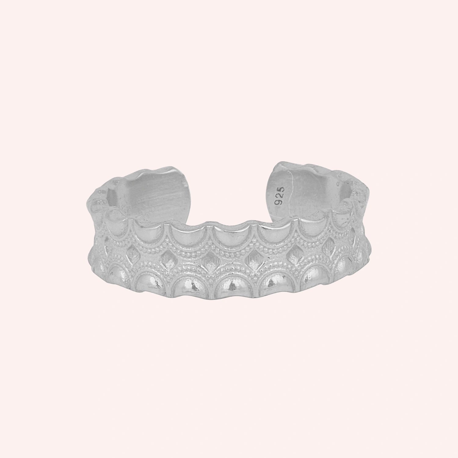 Adjustable_ring_in_sterling_silver_with_handcrafted_deisgn_at_front_angle_on_solid_pink_background