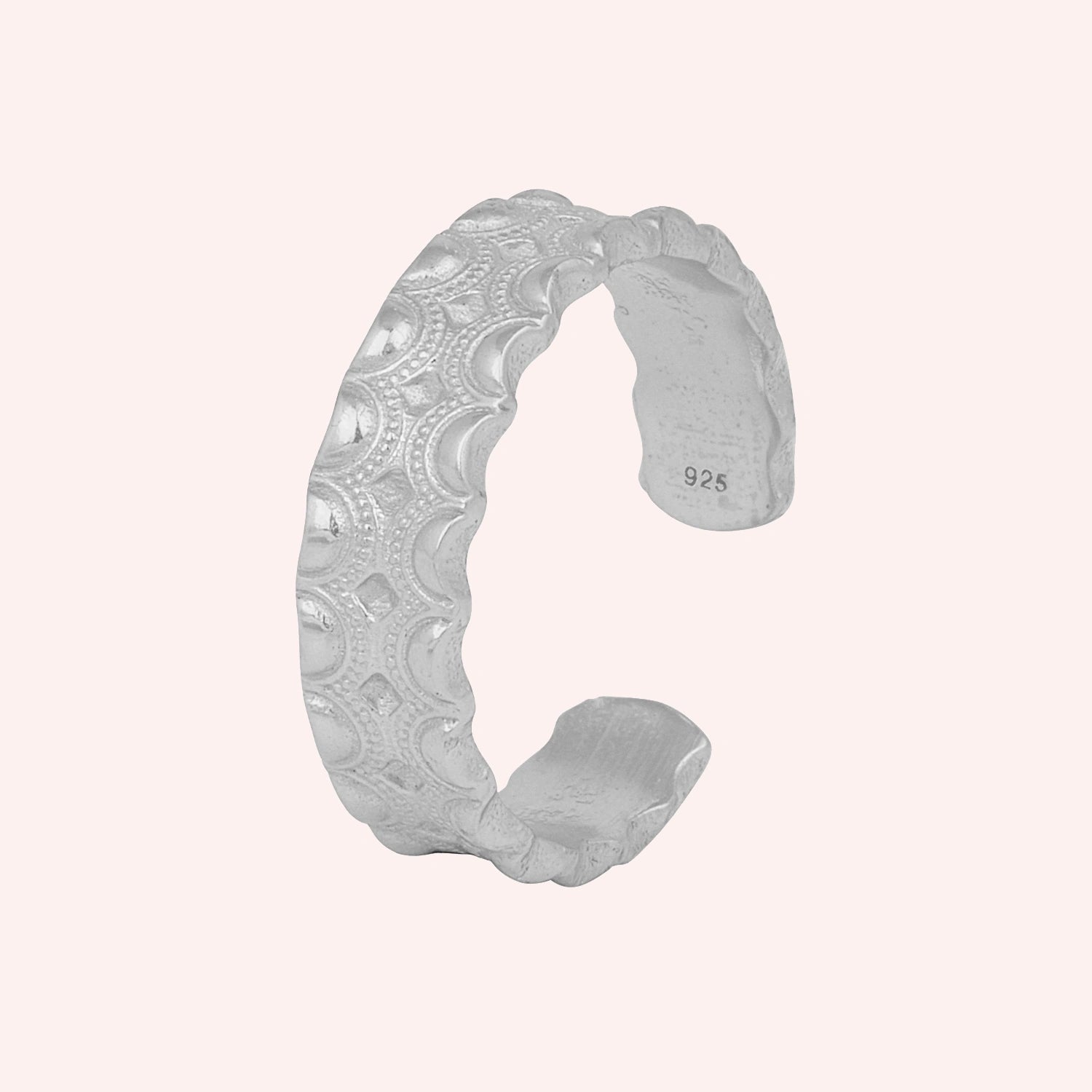 Adjustable_ring_in_sterling_silver_with_handcrafted_deisgn_at_slight_angle_on_solid_pink_background