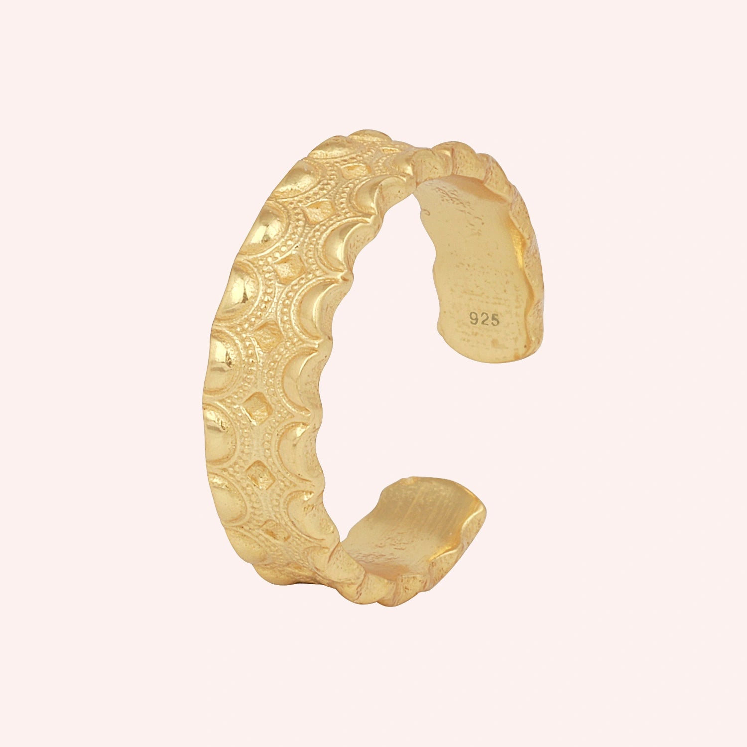 Adjustable_ring_in_gold_plated_silver_with_handcrafted_deisgn_at_slight_angle_on_solid_pink_background