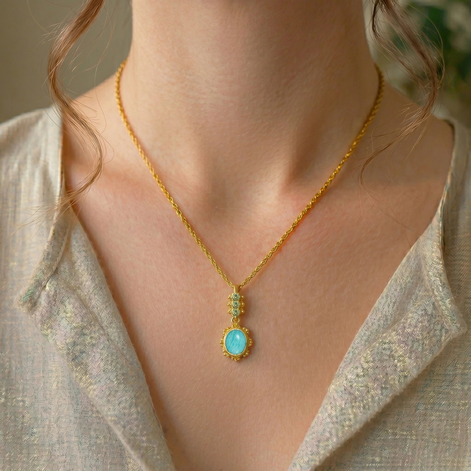 Amazonite_necklace_with_oval_blue_green_stone_gold_plated_silver_pendant_worn_by_a_model