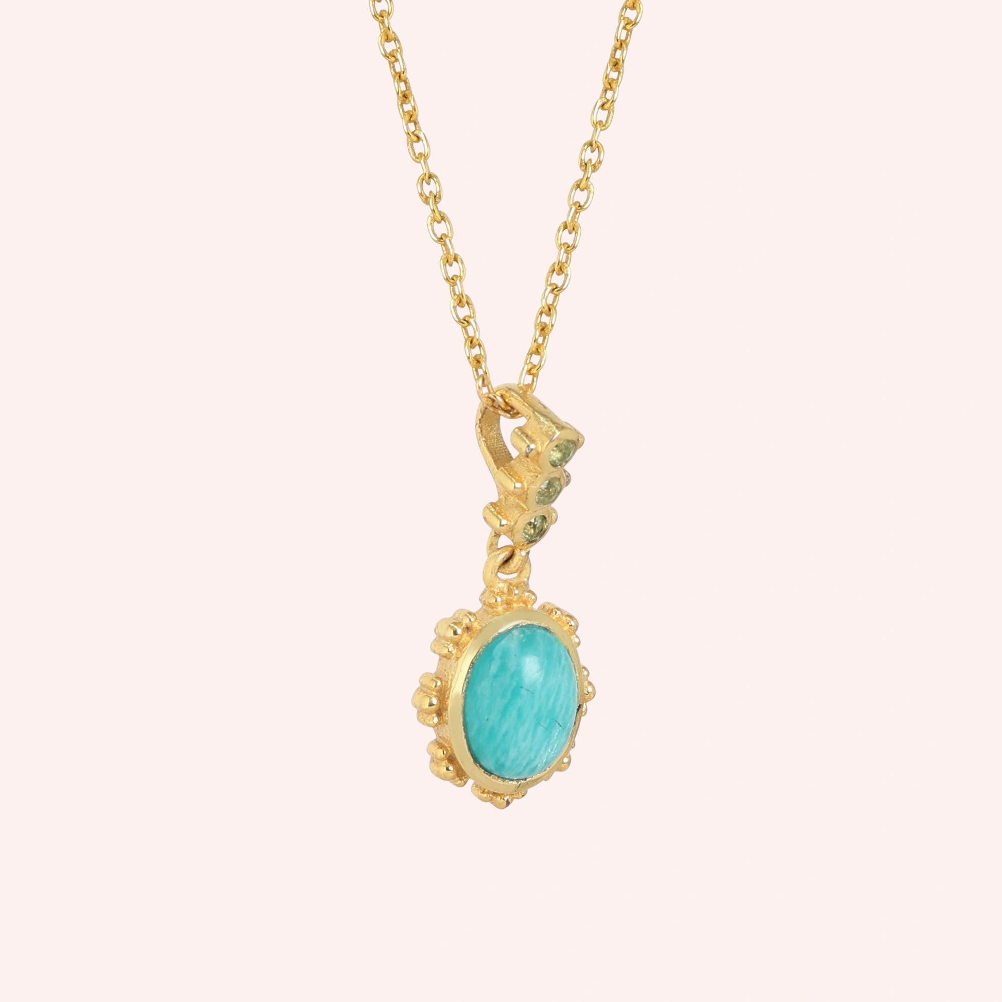 Amazonite_necklace_with_oval_blue_green_stone_gold_plated_silver_pendant_shown_in_slightly_angled_view_on_solid_pink_background