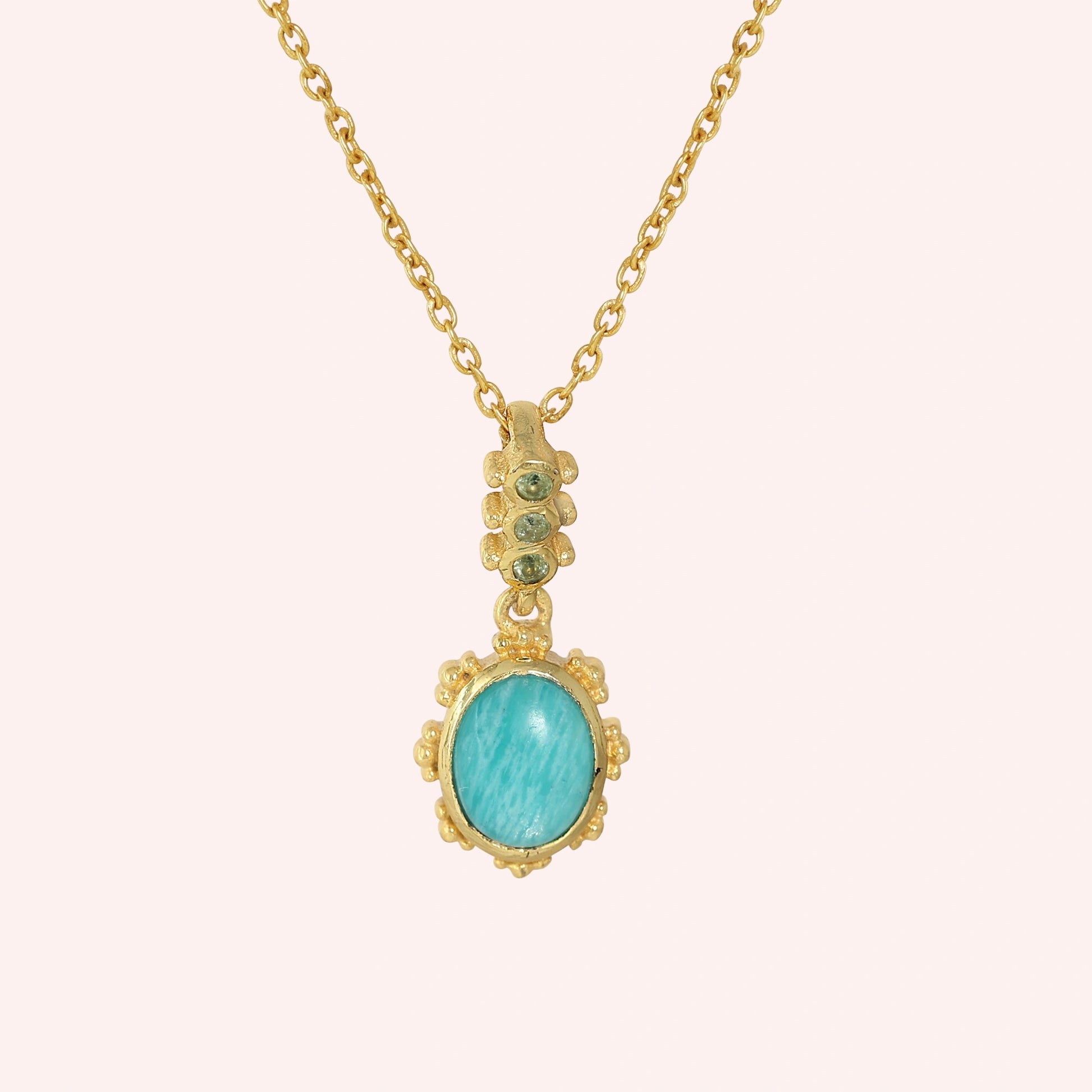 Amazonite_necklace_with_oval_blue_green_stone_gold_plated_silver_pendant_shown_in_front_angle_view_on_solid_pink_background