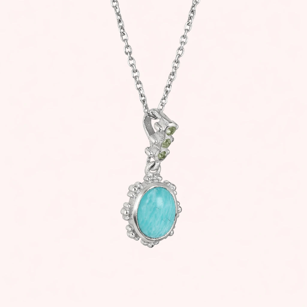 Amazonite_necklace_with_oval_blue_green_stone_sterling_silver_pendant_shown_in_slightly_angled_view_on_solid_pink_background