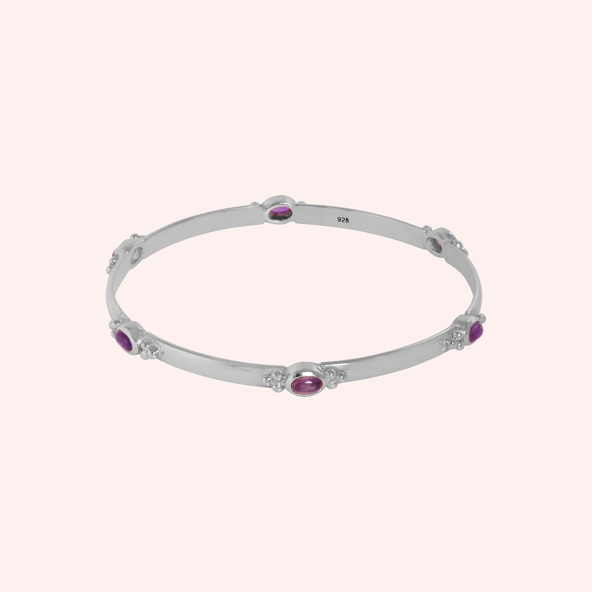 Amethyst_bracelet_in_sterling_silver_with_oval_amethyst_stones_at_front_angle_view_on_solid_pink_background