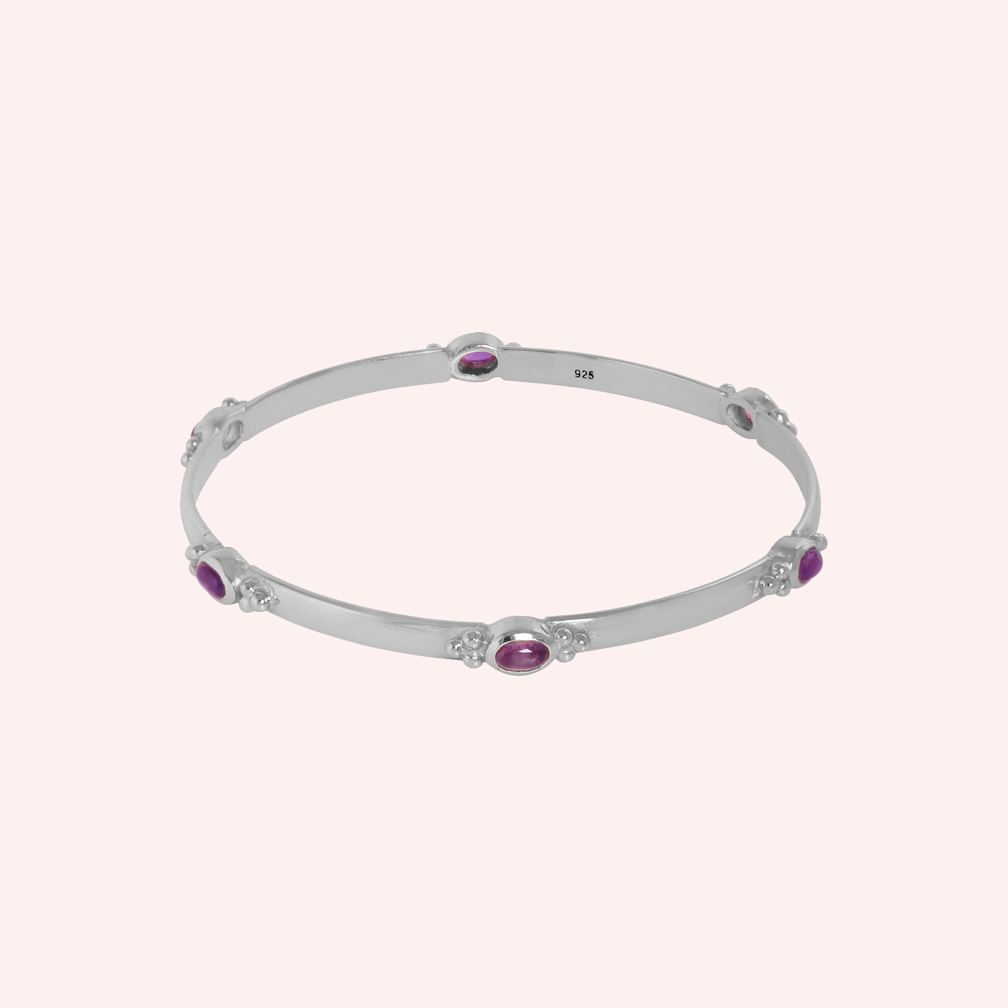 Amethyst_bracelet_in_sterling_silver_with_oval_amethyst_stones_at_front_angle_view_on_solid_pink_background