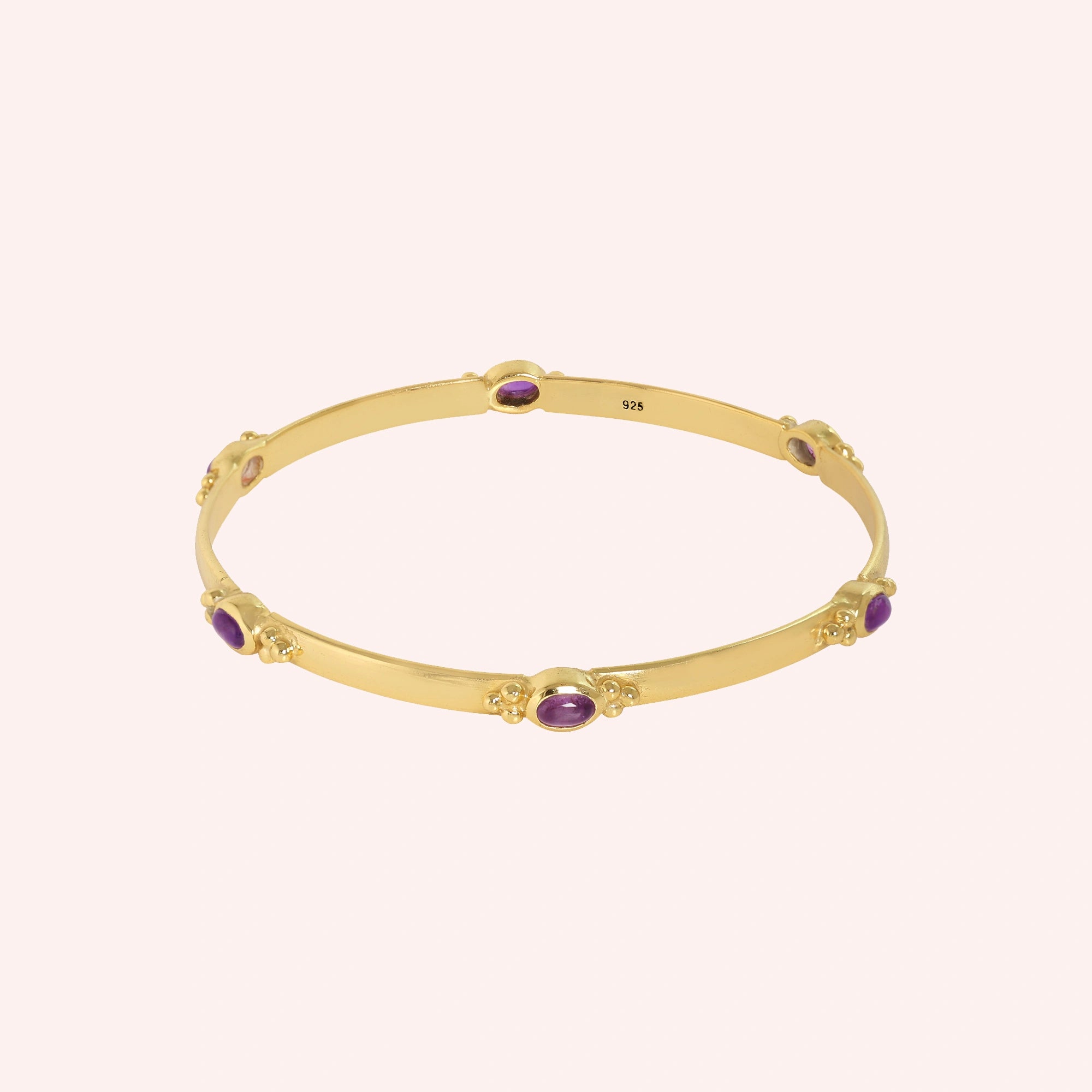 Amethyst_bracelet_in_gold_plated_silver_with_oval_amethyst_stones_at_front_angle_view_on_solid_pink_background