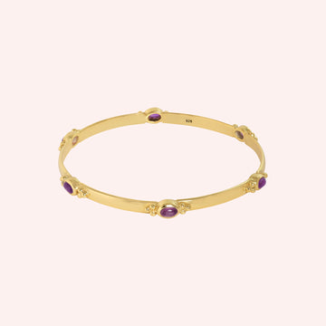Amethyst_bracelet_in_gold_plated_silver_with_oval_amethyst_stones_at_front_angle_view_on_solid_pink_background