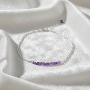 top_angle_amethyst_bracelet_with_amethyst_beads_bracelet_on_soft_white_silk_background_delicate_chain_style