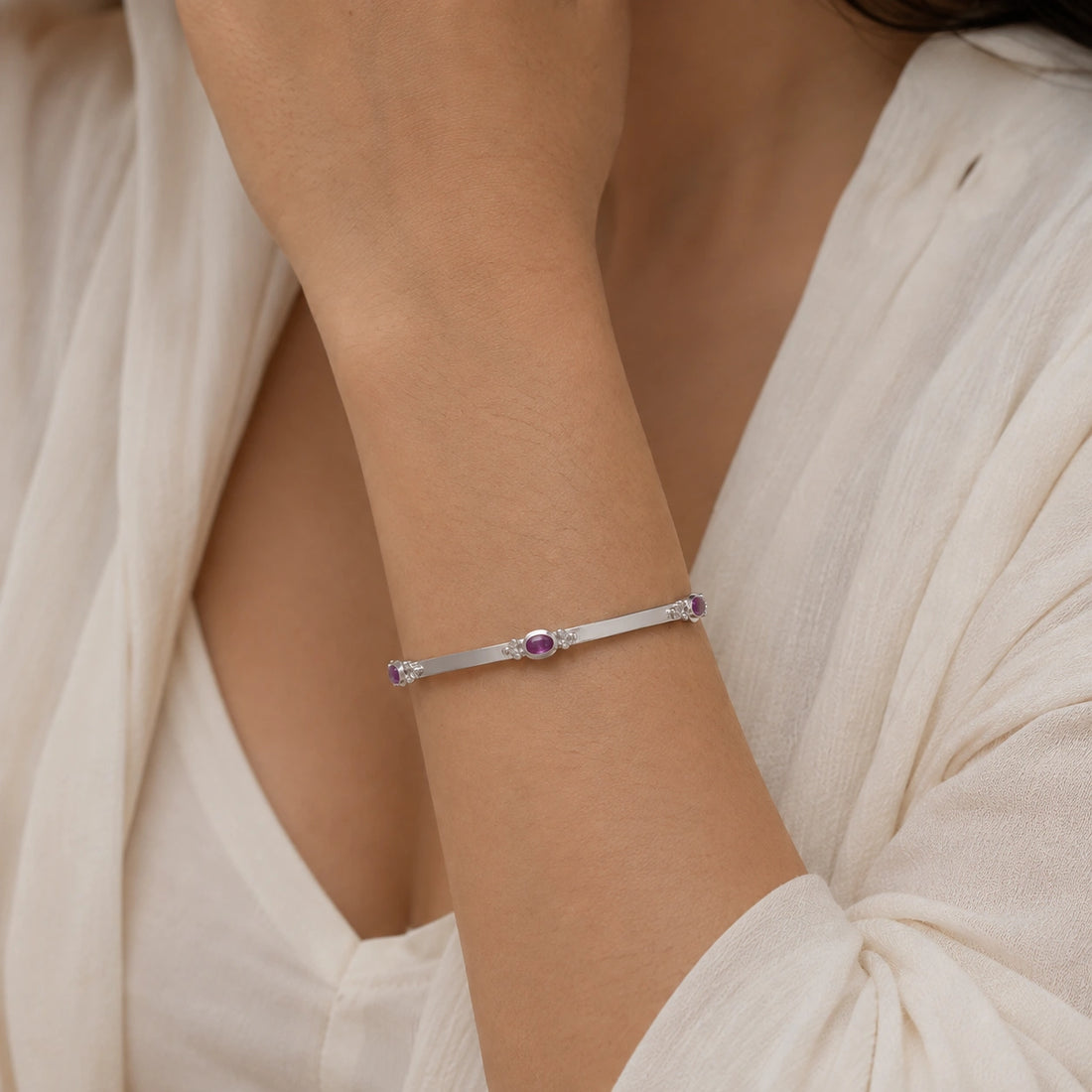 Amethyst_bracelet_in_gold_plated_silver_with_oval_amethyst_stones_at_front_angle_view_on_soft_fabric_background