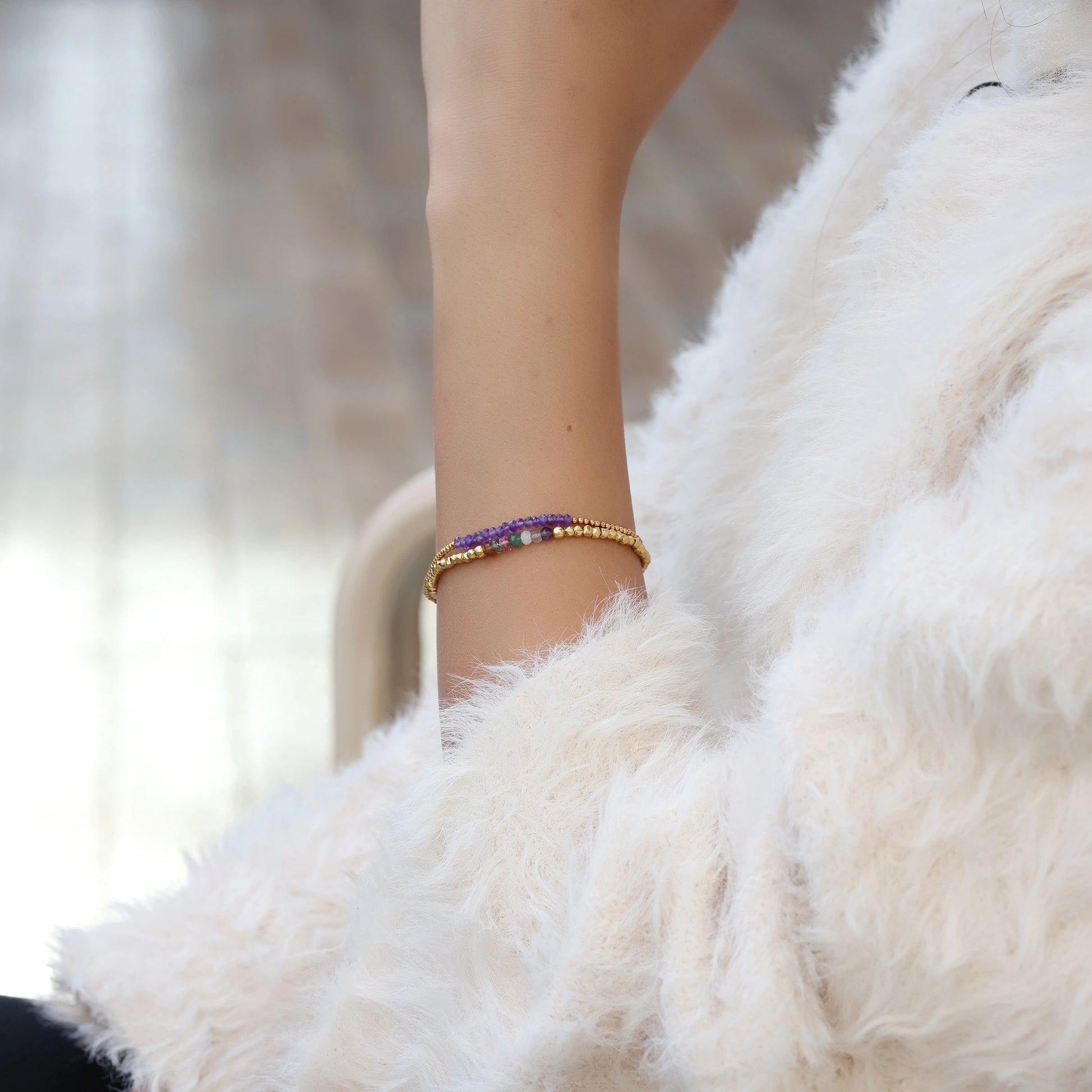 side_angle_amethyst_bracelet_gold_plated_amethyst_beads_bracelet_on_wrist_with_soft_fur_sleeve_background_elegant_style