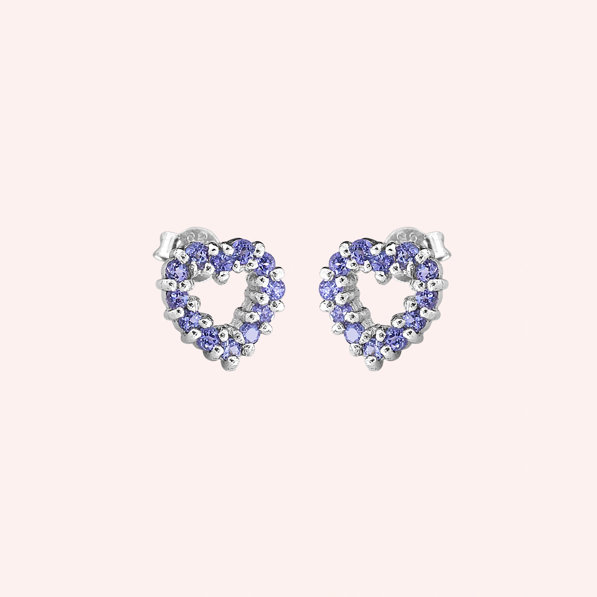 Amethyst_earrings_in_sterling_silver_heart_shape_with_amethyst_stones_at_a_slight_angle_view_on_solid_pink_background