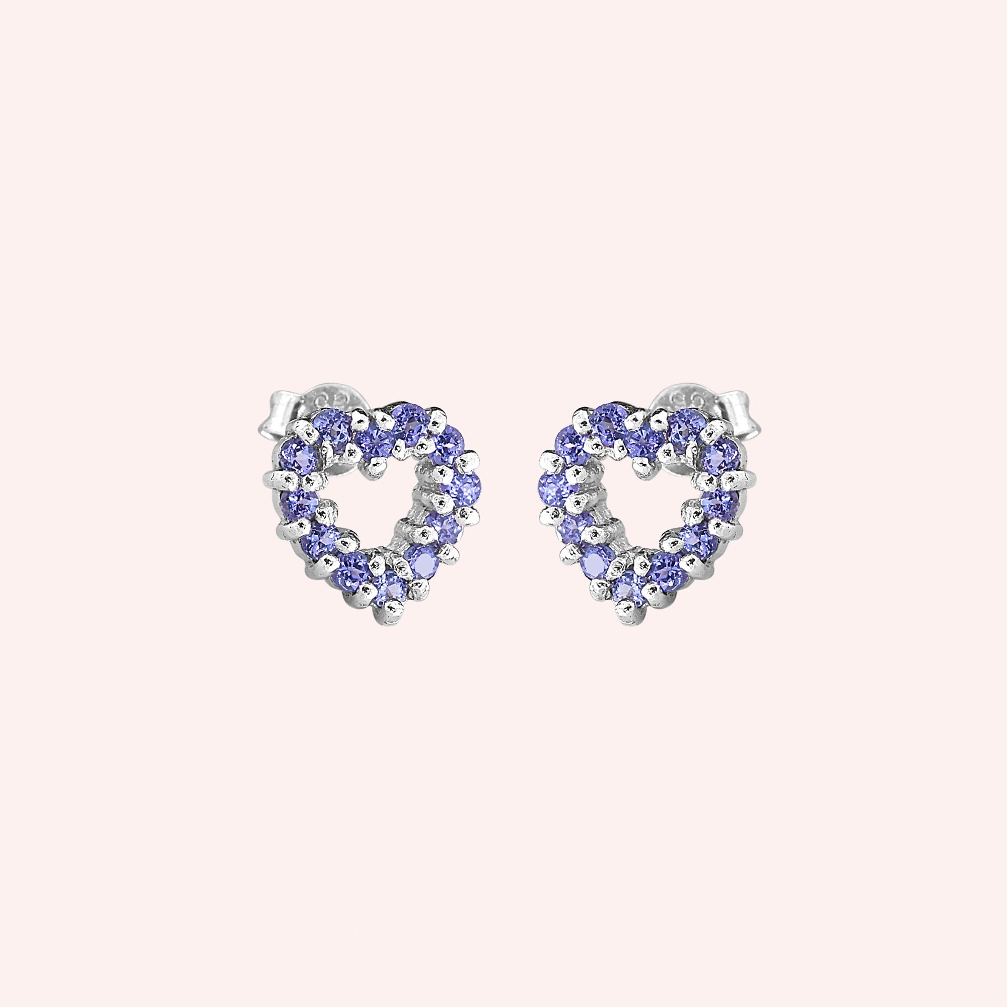 Amethyst_earrings_in_sterling_silver_heart_shape_with_amethyst_stones_at_a_slight_angle_view_on_solid_pink_background