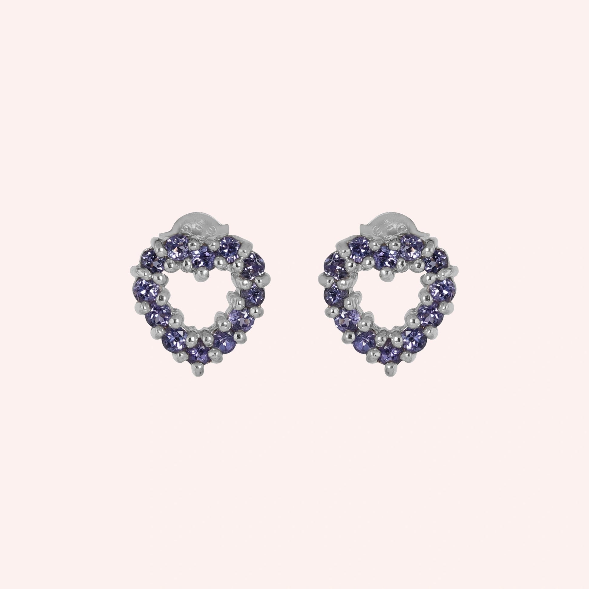 Amethyst_earrings_in_sterling_silver_heart_shape_with_amethyst_stones_at_a_front_angle_view_on_solid_pink_background