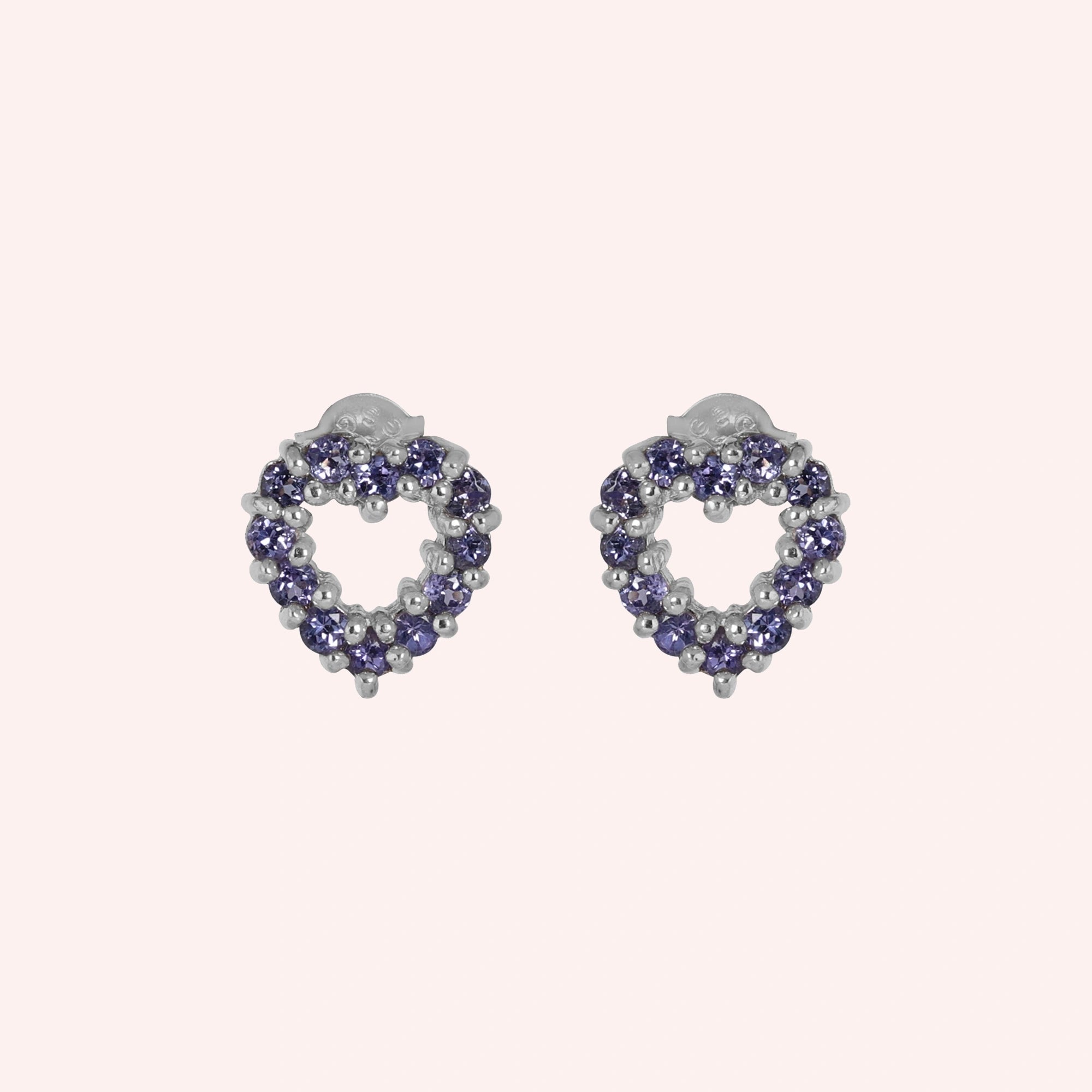Amethyst_earrings_in_sterling_silver_heart_shape_with_amethyst_stones_at_a_front_angle_view_on_solid_pink_background