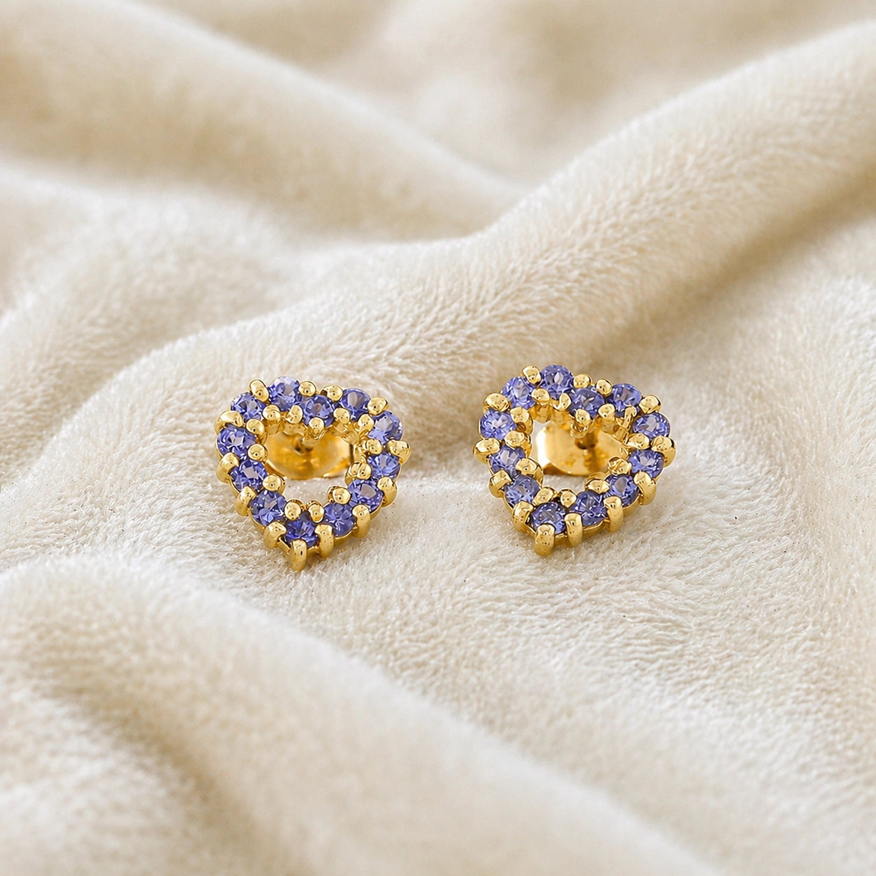 Amethyst_earrings_in_gold_plated_silver_heart_shape_with_amethyst_stones_at_a_front_angle_view_on_soft_fabric_background