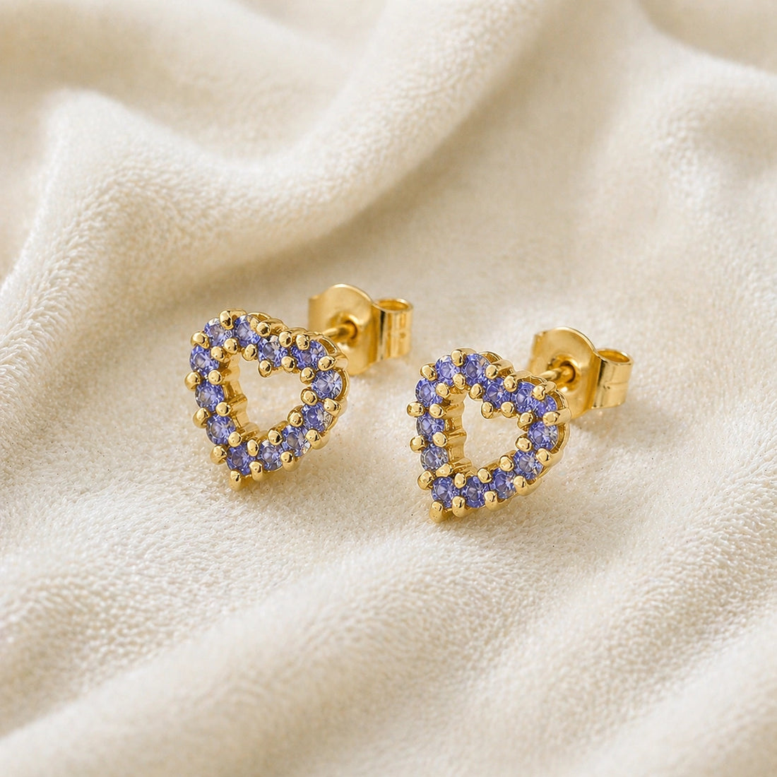 Amethyst_earrings_in_gold_plated_silver_heart_shape_with_amethyst_stones_at_a_slight_angle_view_on_soft_fabric_background