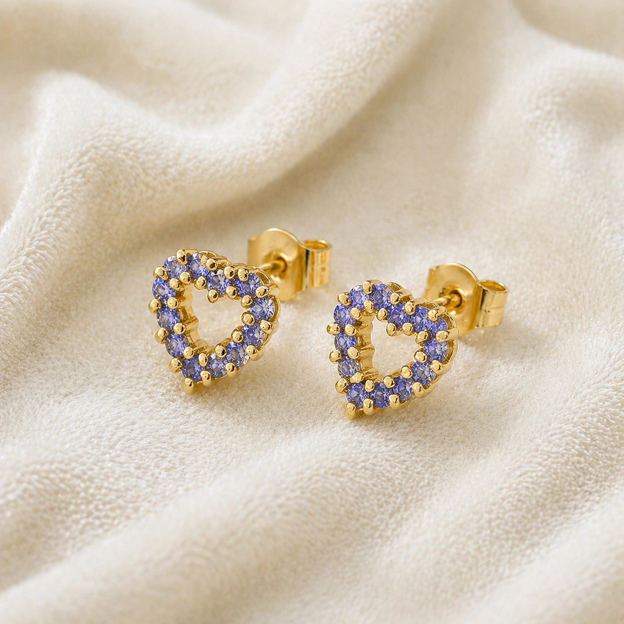 Amethyst_earrings_in_gold_plated_silver_heart_shape_with_amethyst_stones_at_a_slight_angle_view_on_soft_fabric_background