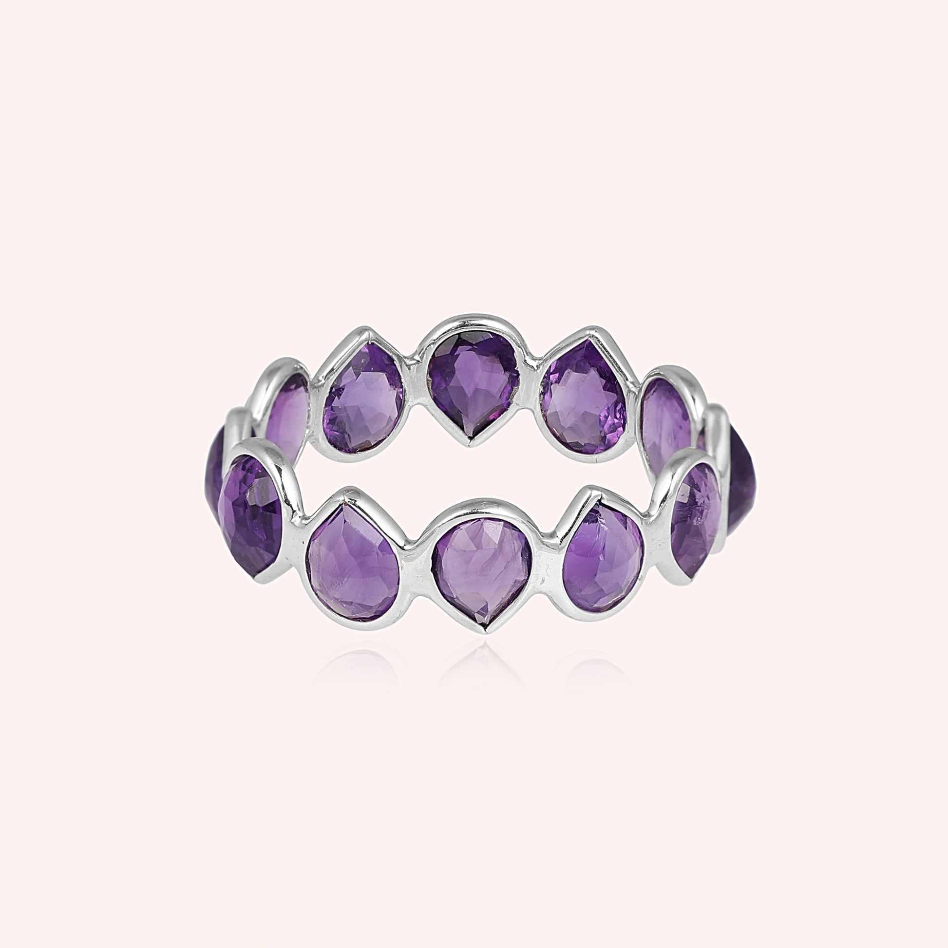 Horizontal shot of a sterling silver amethyst ring on a light pink background showcasing pear cut amethyst stones in a silver setting