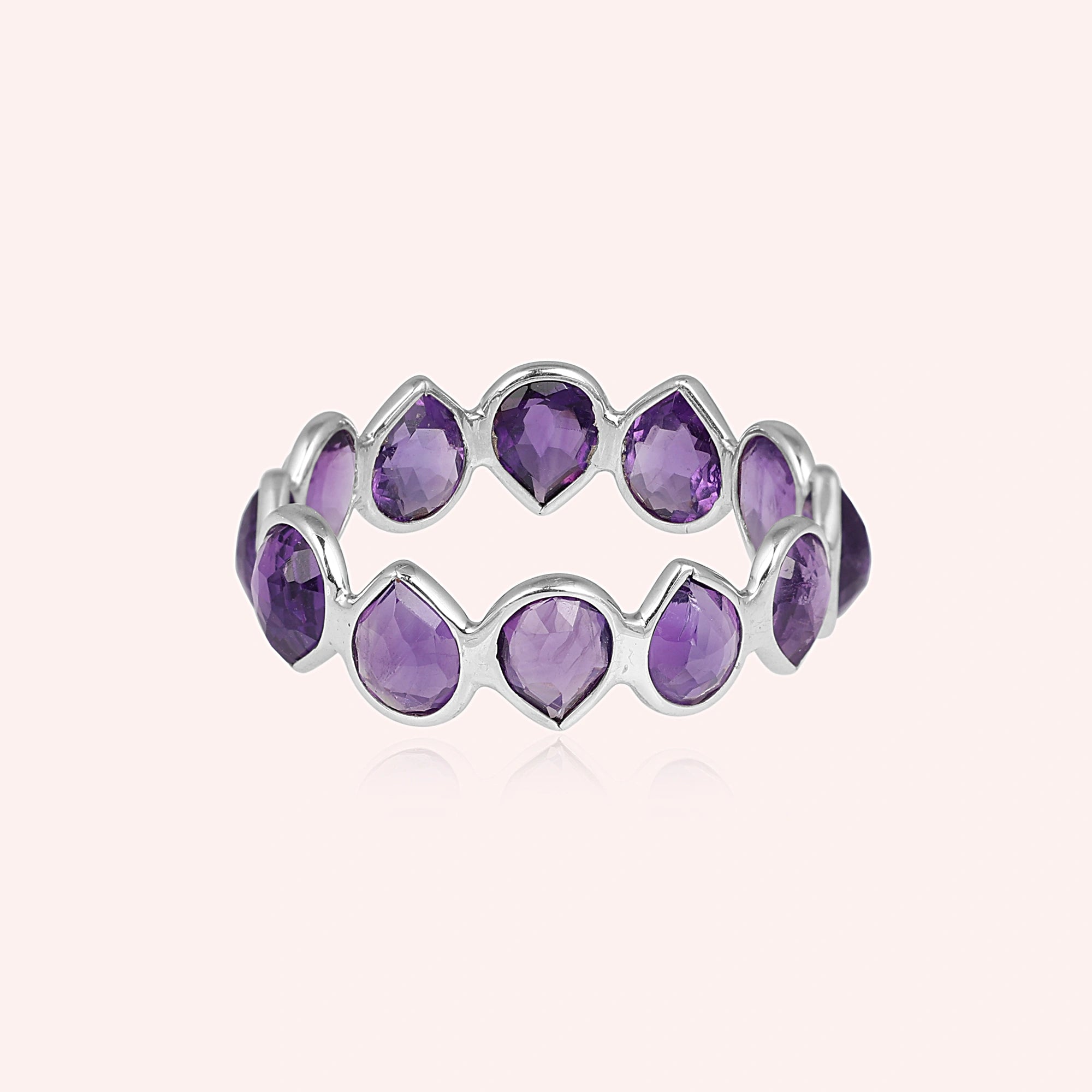 Horizontal shot of a sterling silver amethyst ring on a light pink background showcasing pear cut amethyst stones in a silver setting