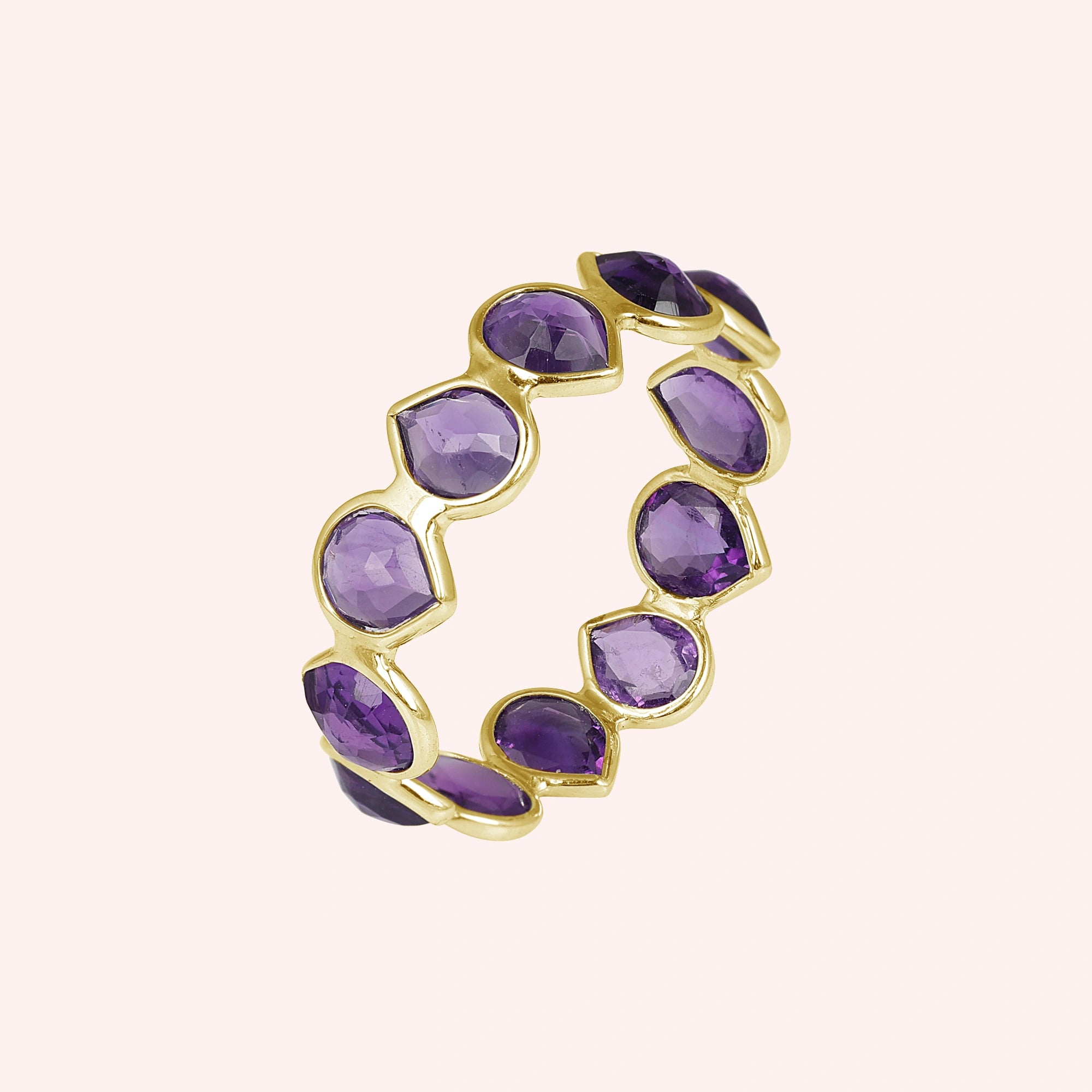 Angled shot of a gold-plated sterling silver amethyst ring on a light pink background showcasing pear cut purple amethyst stones