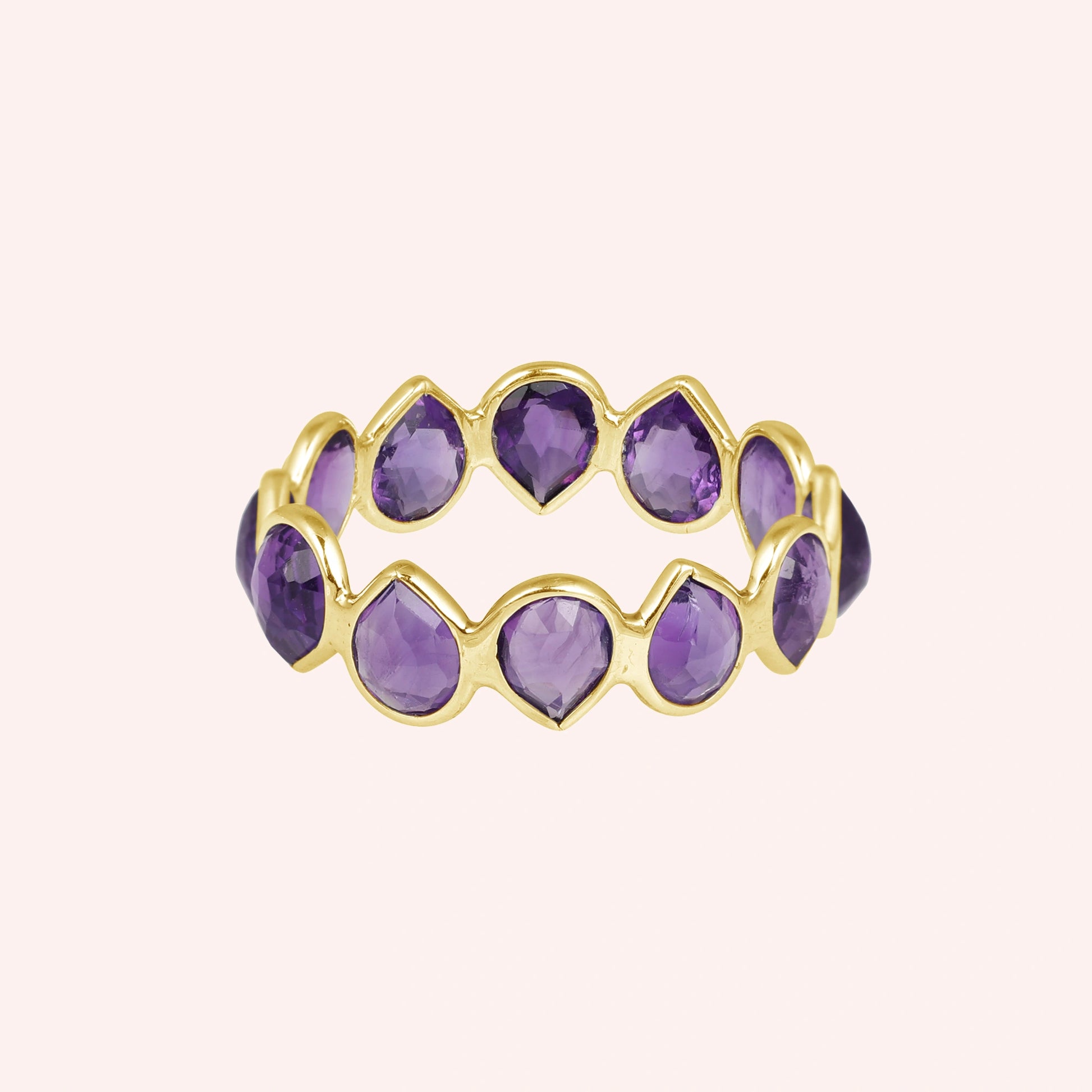 Horizontal shot of a gold-plated sterling silver amethyst ring on a light pink background with pear cut purple amethyst stones
