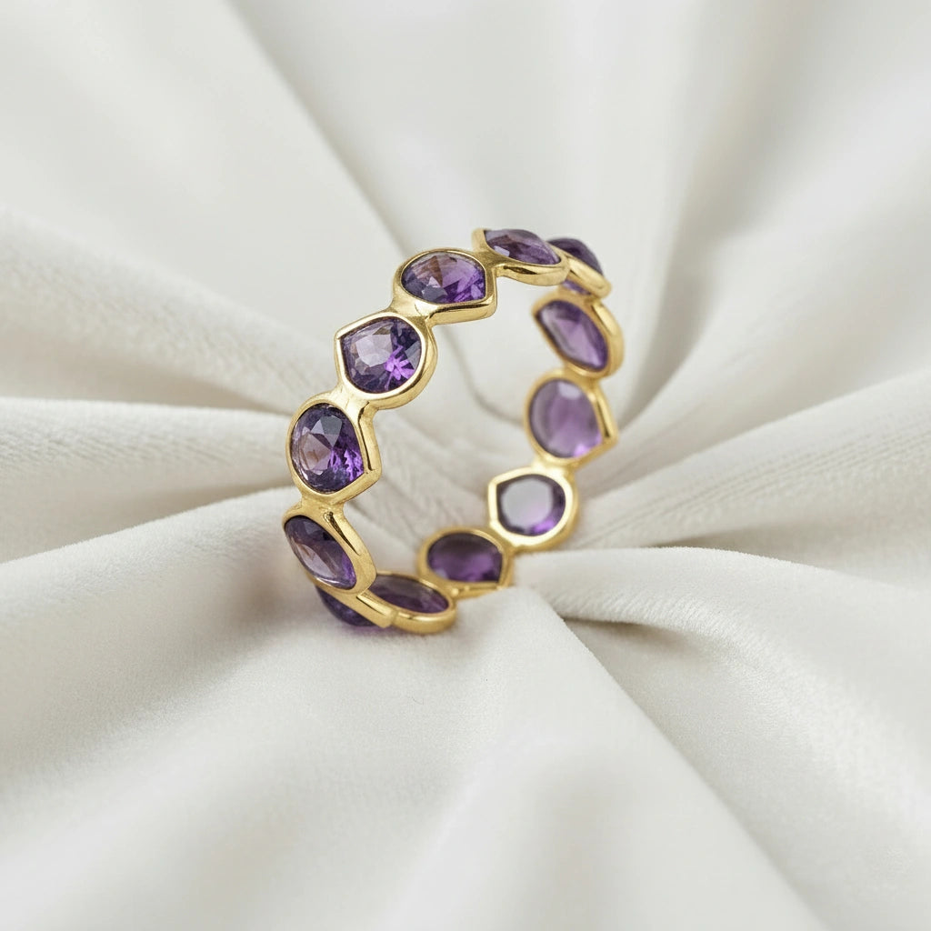 Angled close up shot of a gold-plated sterling silver amethyst ring on a white velvet background with pear cut amethyst stones