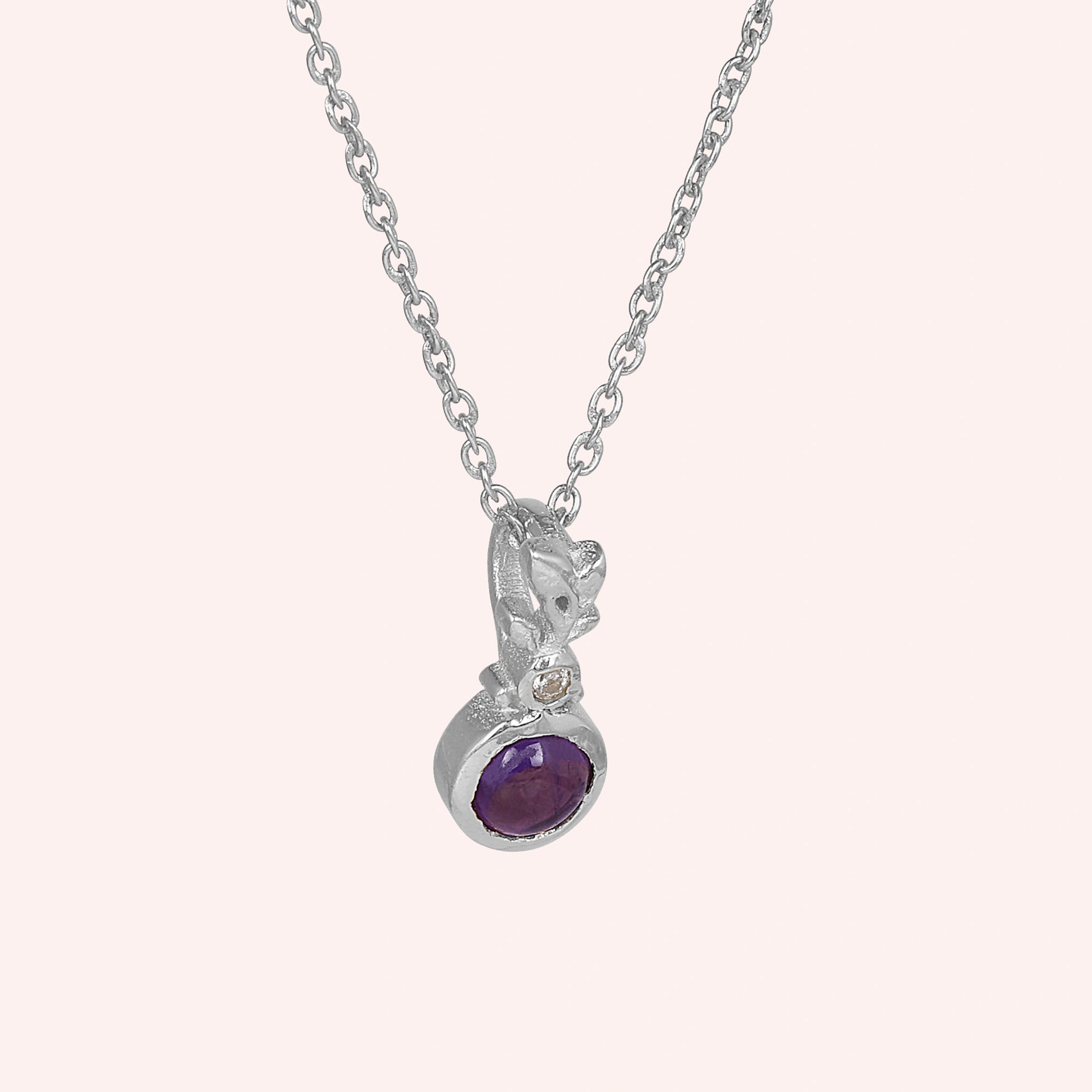 Amethyst_necklace_in_sterling_silver_with_amethyst_and_crystal_stones_at_slight_angle_view_on_solid_pink_background