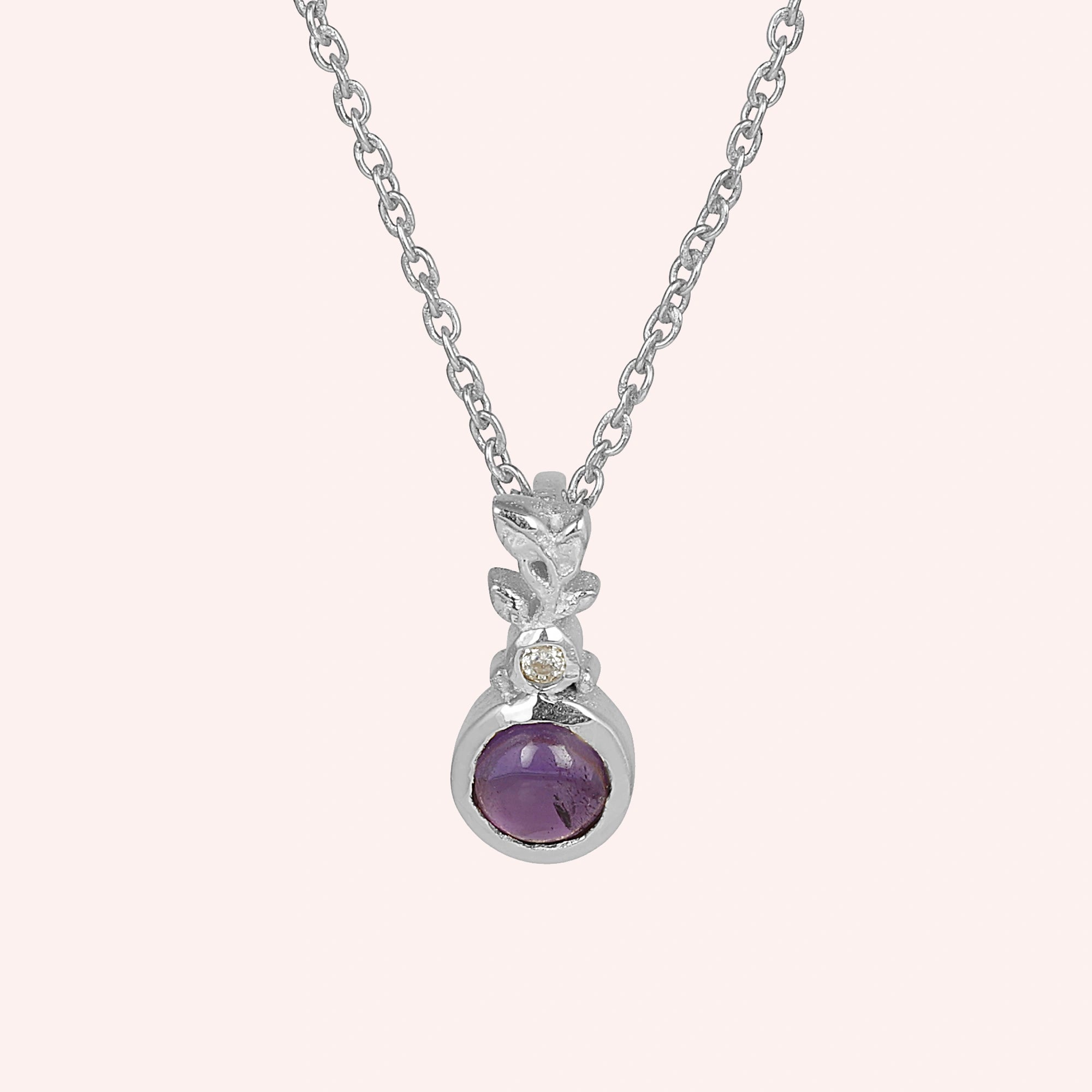 Amethyst_necklace_in_sterling_silver_with_amethyst_and_crystal_stones_at_front_angle_view_on_solid_pink_background