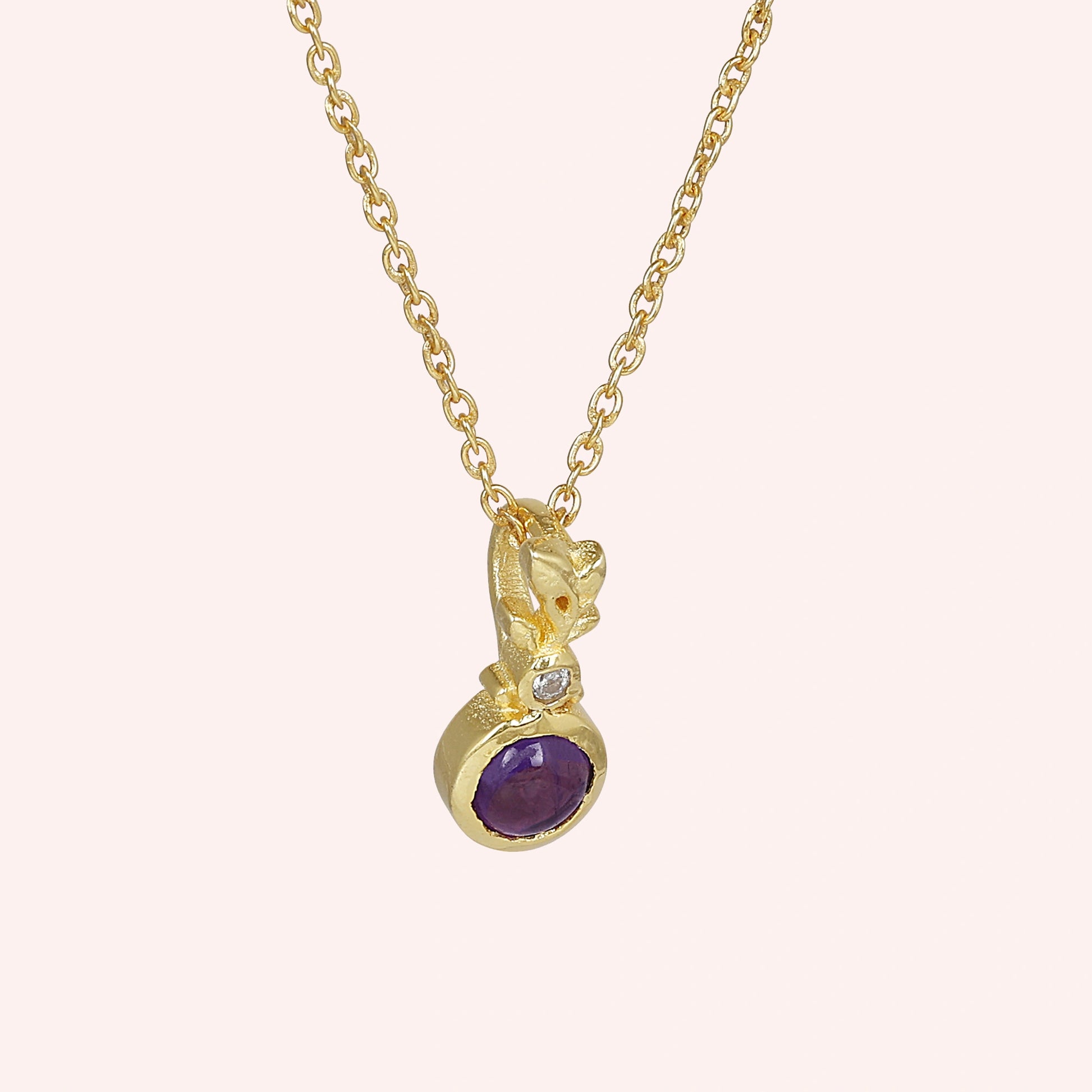 Amethyst_necklace_in_gold_plated_silver_with_amethyst_and_crystal_stones_at_slight_angle_view_on_solid_pink_background