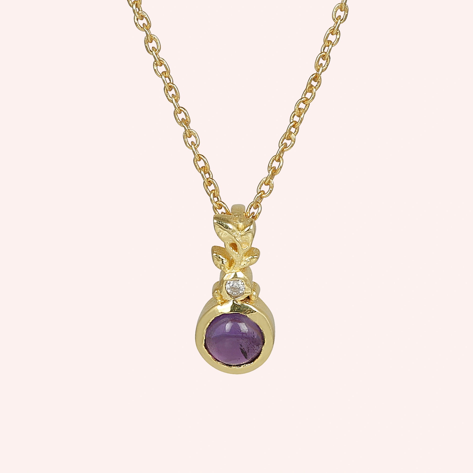 Amethyst_necklace_in_gold_plated_silver_with_amethyst_and_crystal_stones_at_front_angle_view_on_solid_pink_background