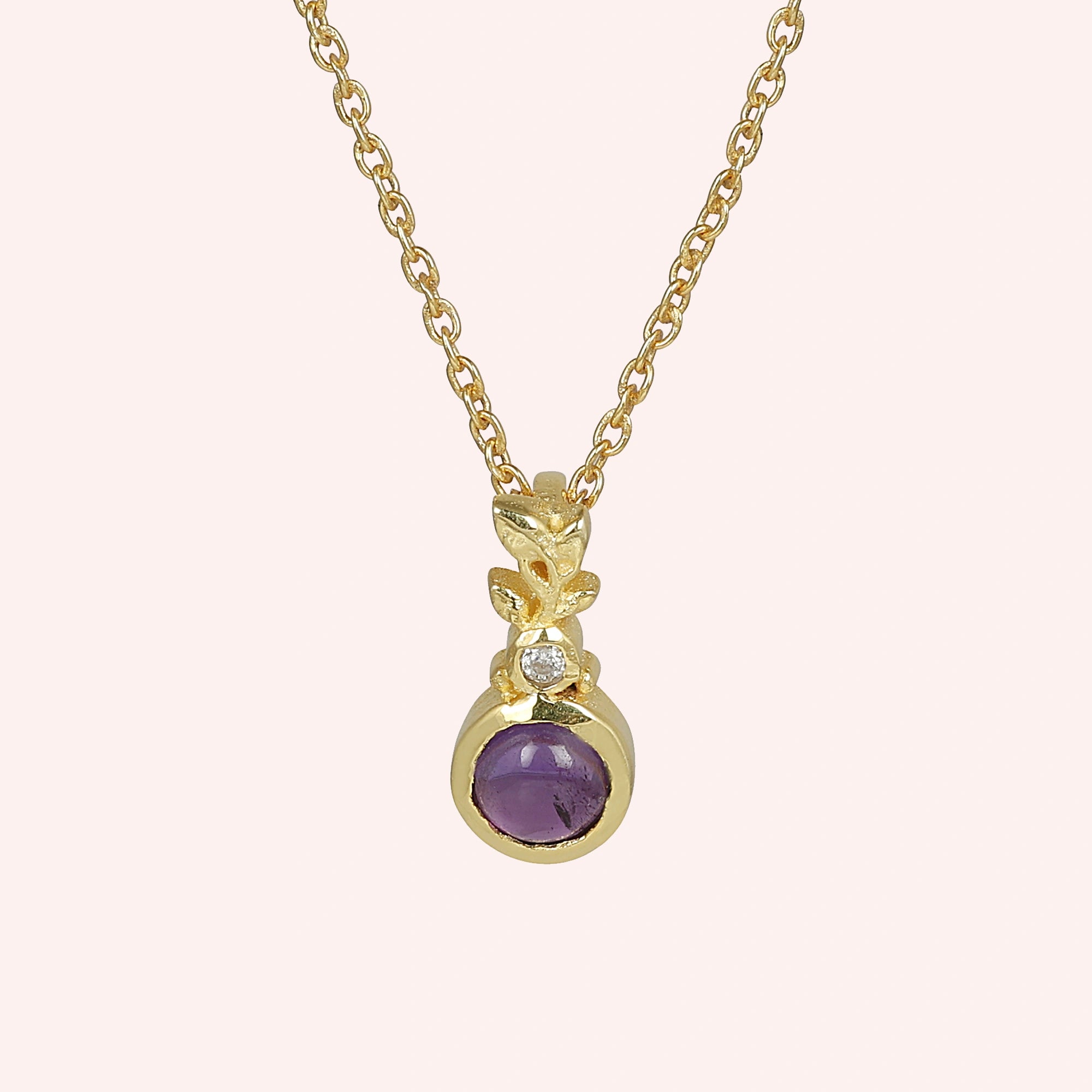 Amethyst_necklace_in_gold_plated_silver_with_amethyst_and_crystal_stones_at_front_angle_view_on_solid_pink_background