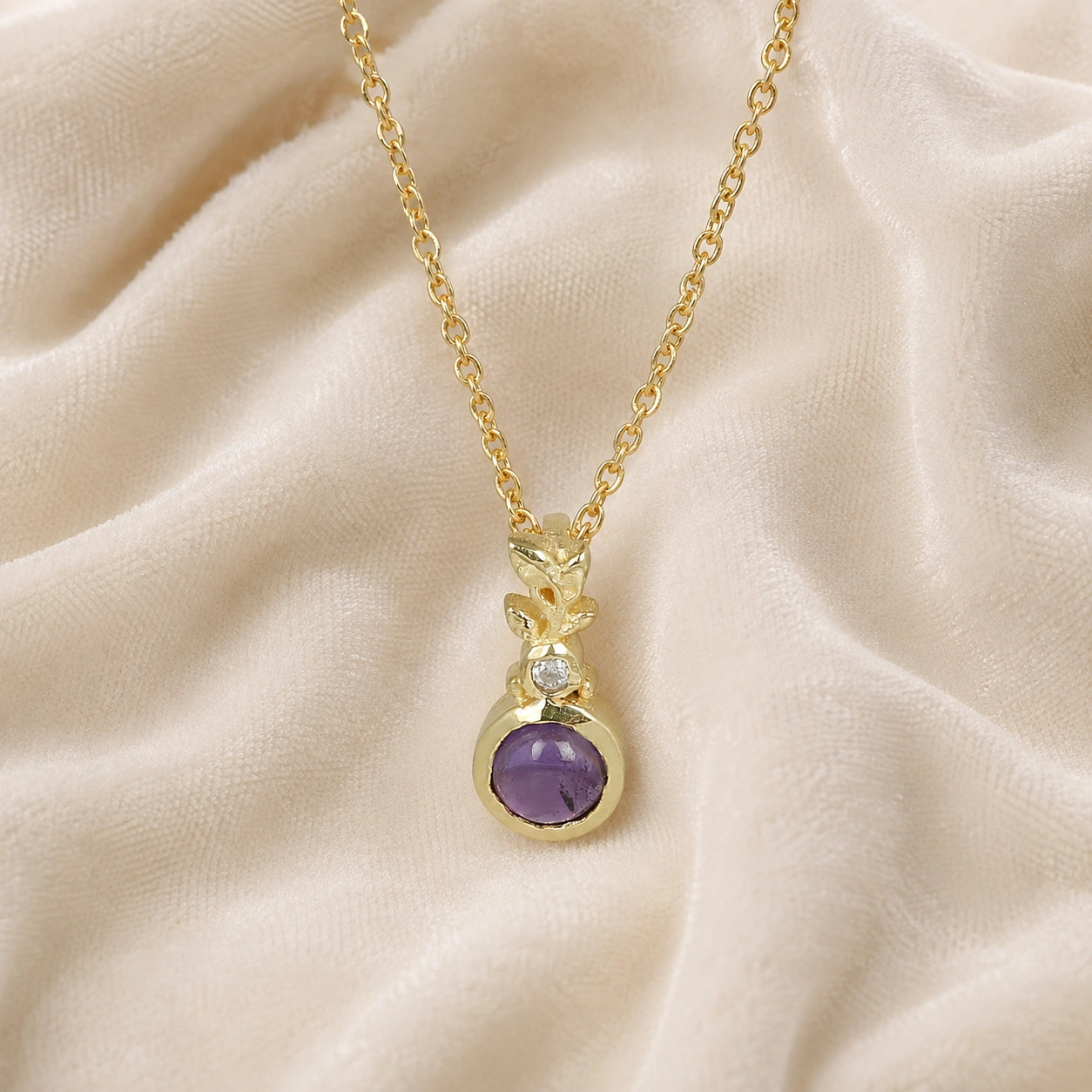 Amethyst_necklace_in_gold_plated_silver_with_amethyst_and_crystal_stones_at_front_angle_view_on_soft_fabric_background