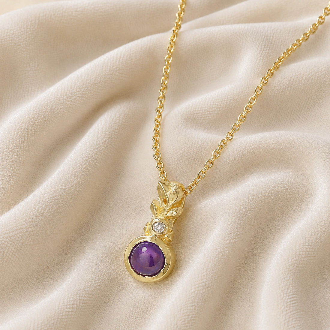 Amethyst_necklace_in_gold_plated_silver_with_amethyst_and_crystal_stones_at_slight_angle_view_on_soft_fabric_background