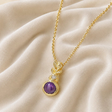 Amethyst_necklace_in_gold_plated_silver_with_amethyst_and_crystal_stones_at_slight_angle_view_on_soft_fabric_background