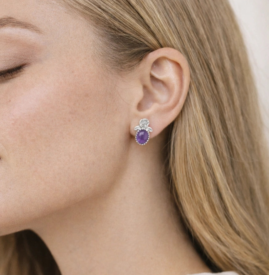 Side_view_amethyst_stud_earrings_with_oval_purple_gemstone_set_in_silver_flower_stud_earrings_worn_on_model_soft_light_background