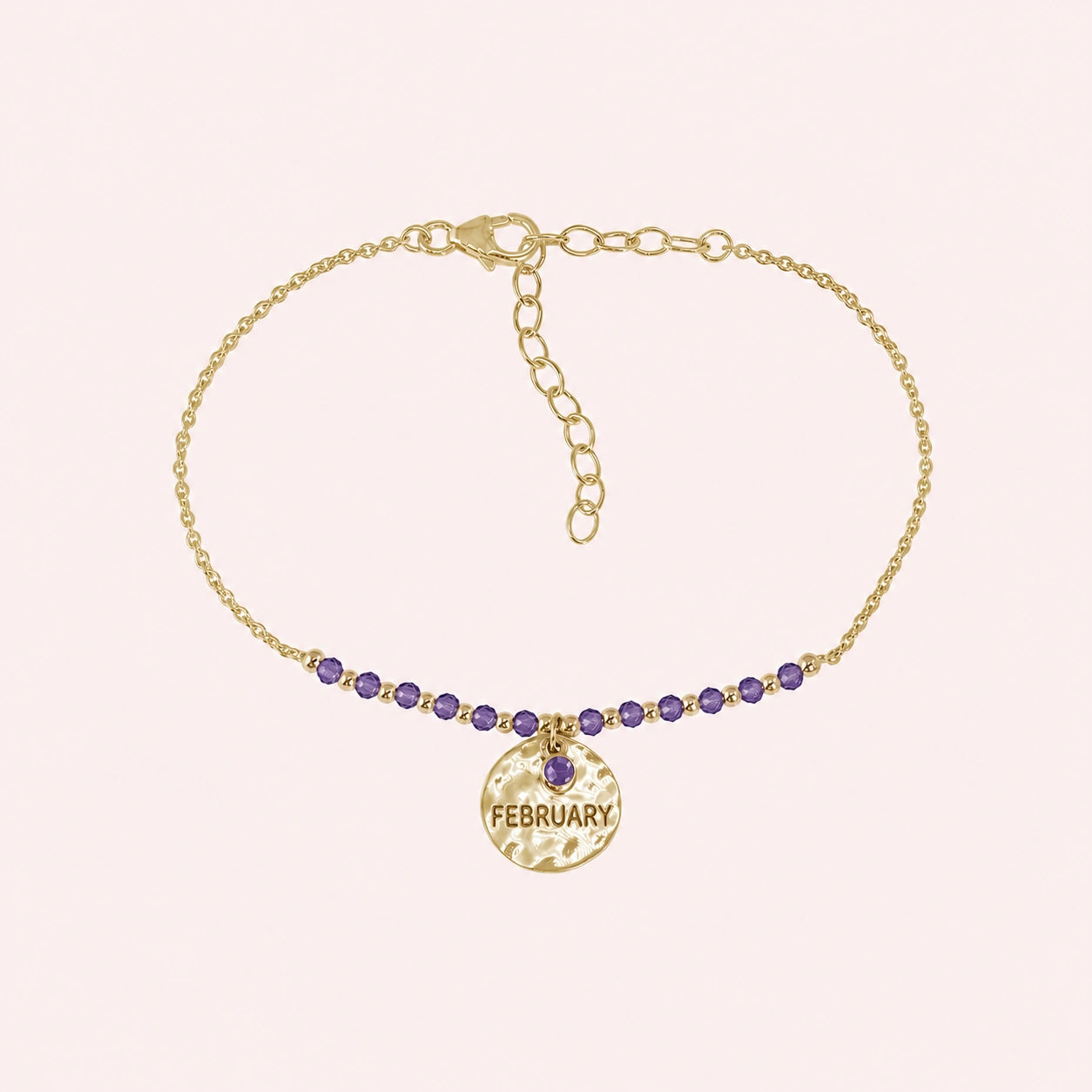 Birthstone_bracelet_in_gold_plated_silver_with_February_charm_and_amethyst_beads_on_fine_chain_on_solid_pink_background