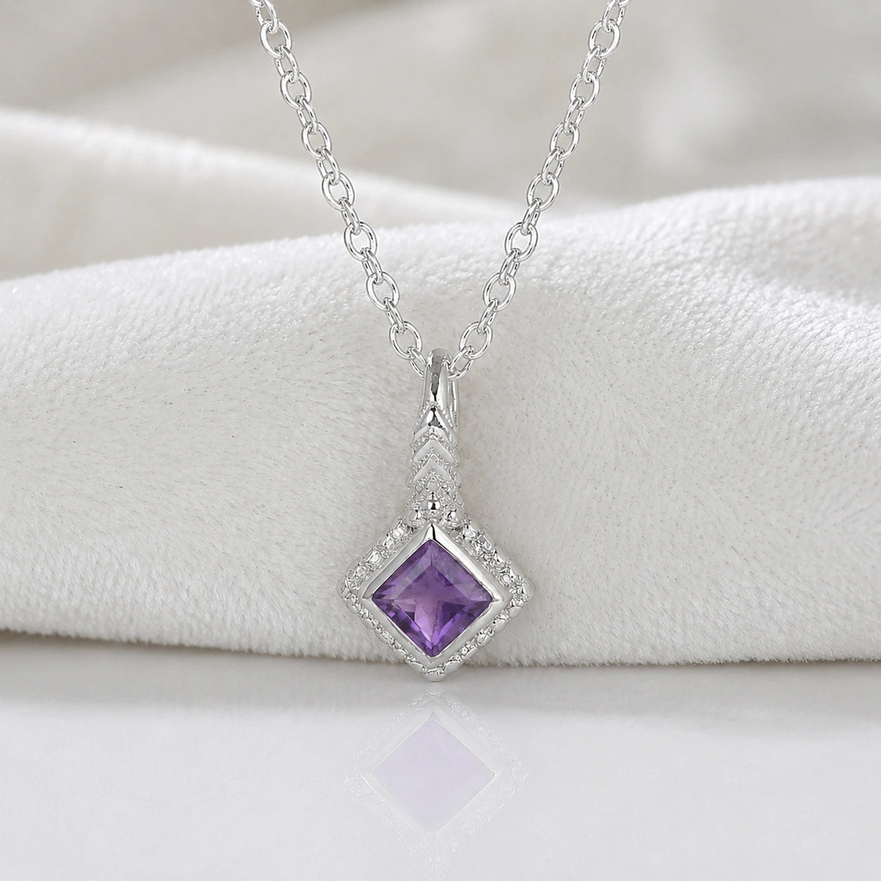 Birthstone_necklace_in_sterling_silver_with_square_cut_amethyst_pendant_in_front_angle_view_on_soft_white_fabric_background