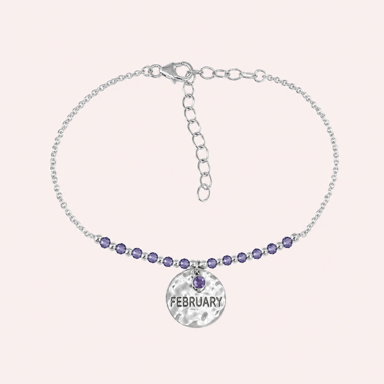 Birthstone_bracelet_in_sterling_silver_with_February_charm_and_amethyst_beads_on_fine_chain_on_solid_pink_background