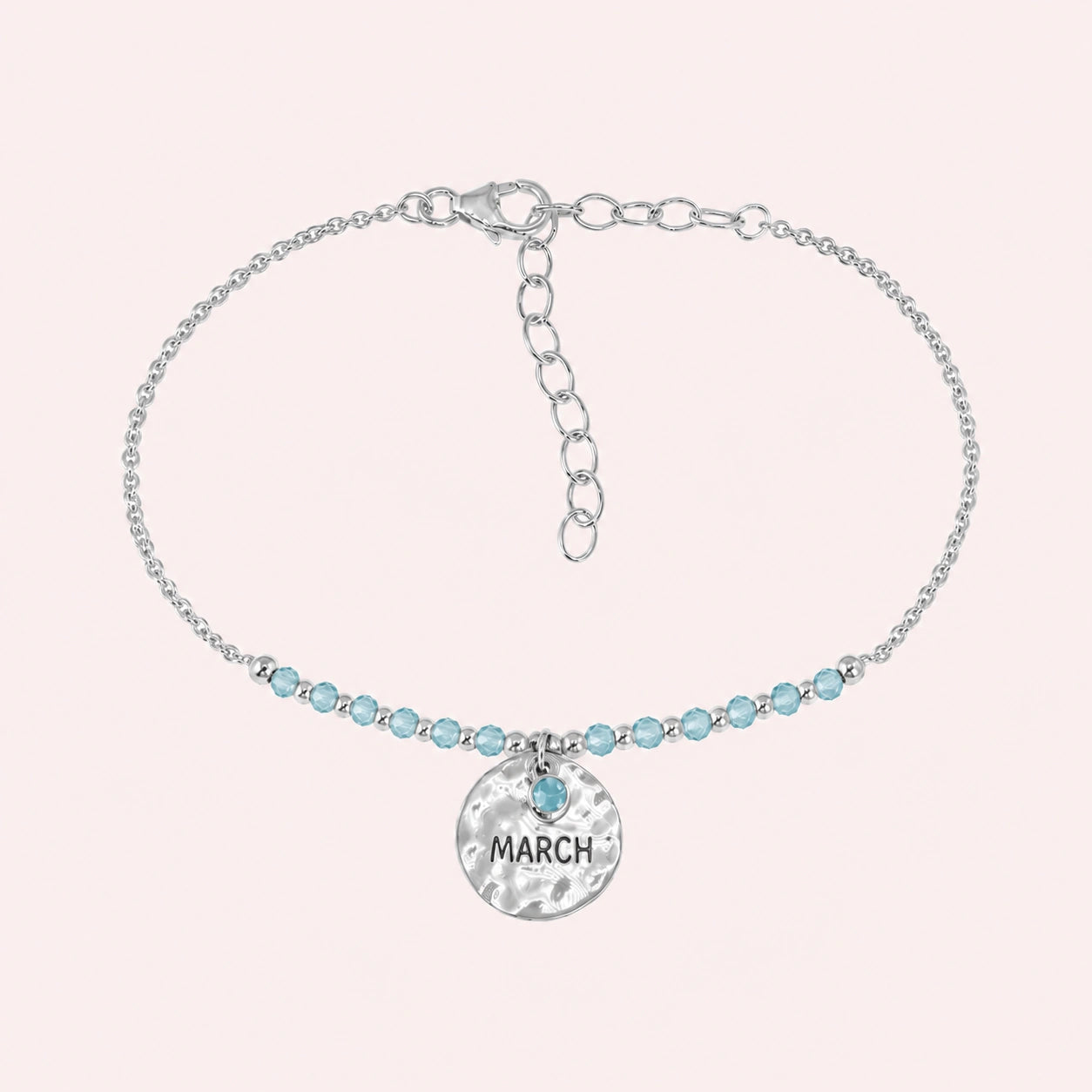 Birthstone_bracelet_in_sterling_silver_with_March_charm_and_aqua_marine_beads_on_fine_chain_on_solid_pink_background