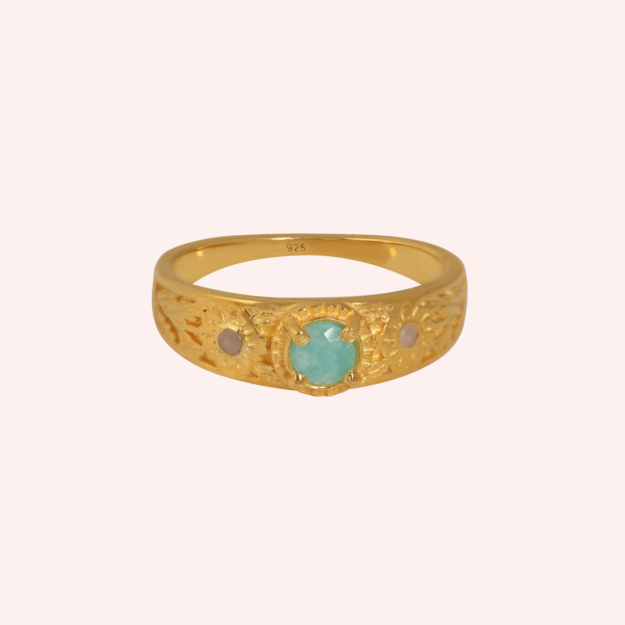 Art-deco-ring-in-gold-plated-silver-with-blue-center-stone-and-textured-band-front-angle-view-on-solid-pink-background