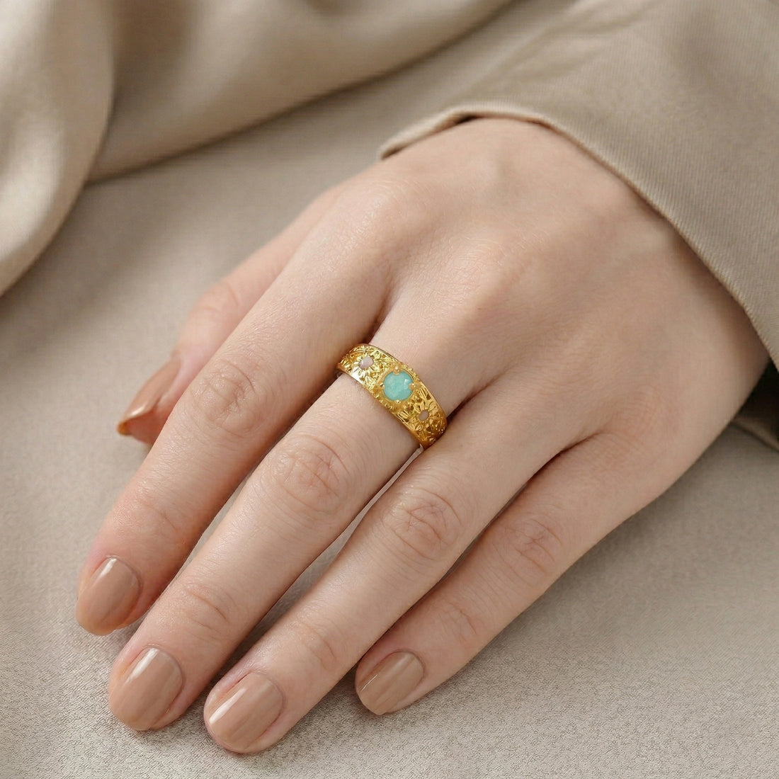 Art-deco-ring-in-gold-plated-silver-with-blue-center-stone-and-textured-band-side-angled-view-on-soft-white-fabric-background