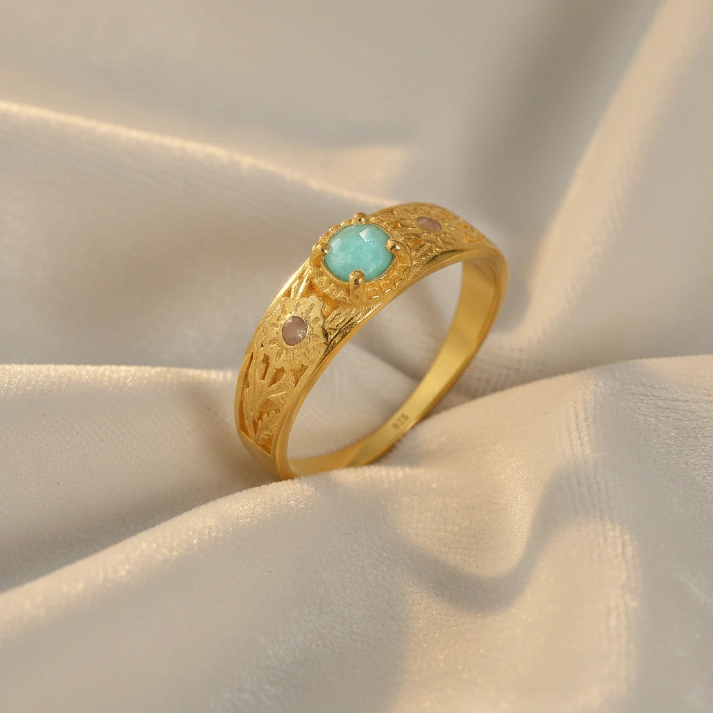 Art-deco-ring-in-gold-plated-silver-with-blue-center-stone-and-textured-band-side-angled-view-on-soft-white-fabric-background