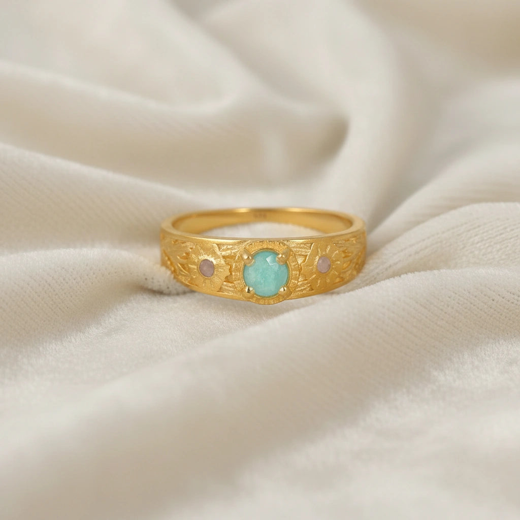 Art-deco-ring-in-gold-plated-silver-with-blue-center-stone-and-textured-band-front-angle-view-on-soft-white-fabric-background