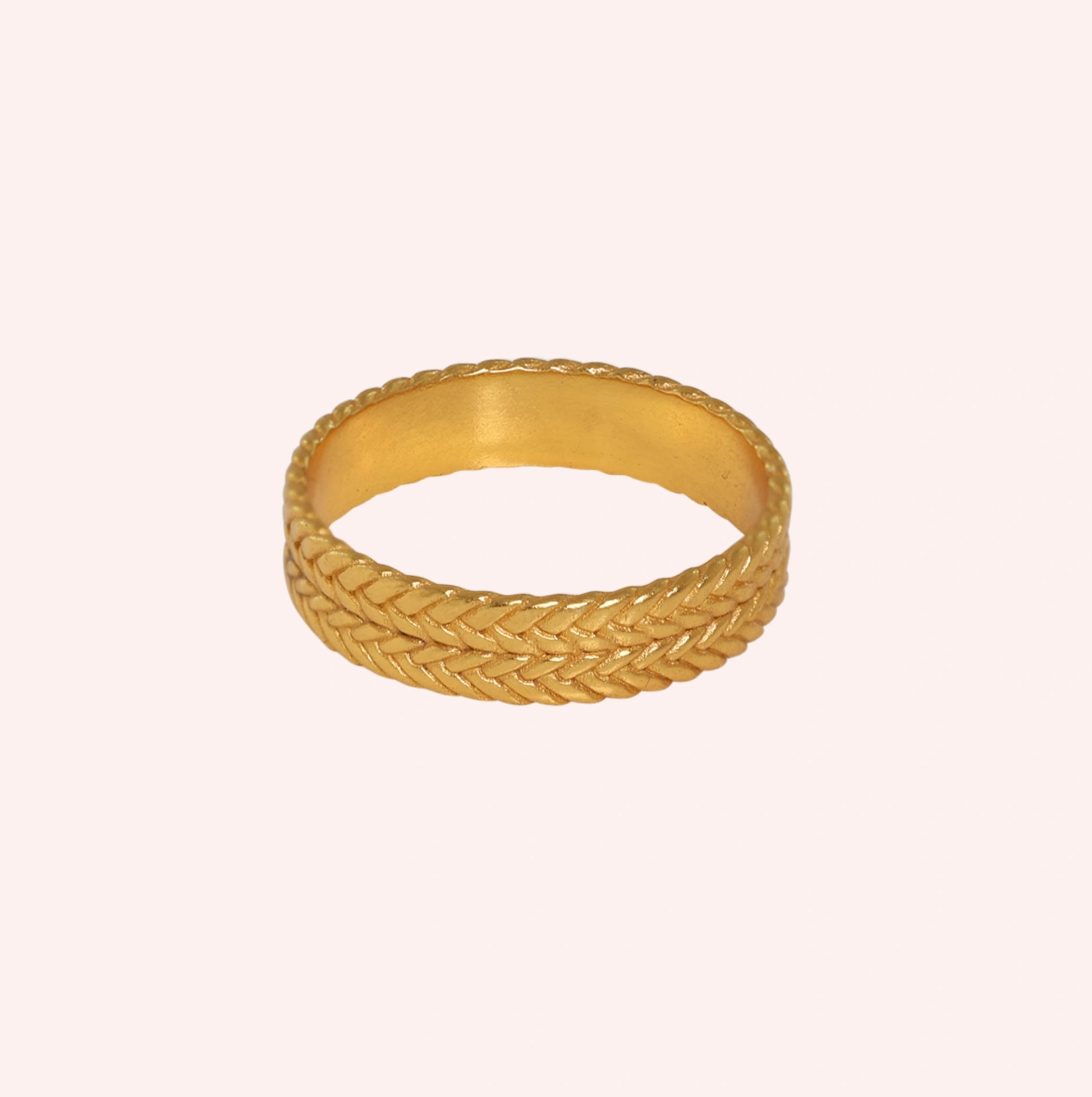 Band_ring_in_gold_plated_silver_with_braided_design_at_front_angle_on_solid_pink_background